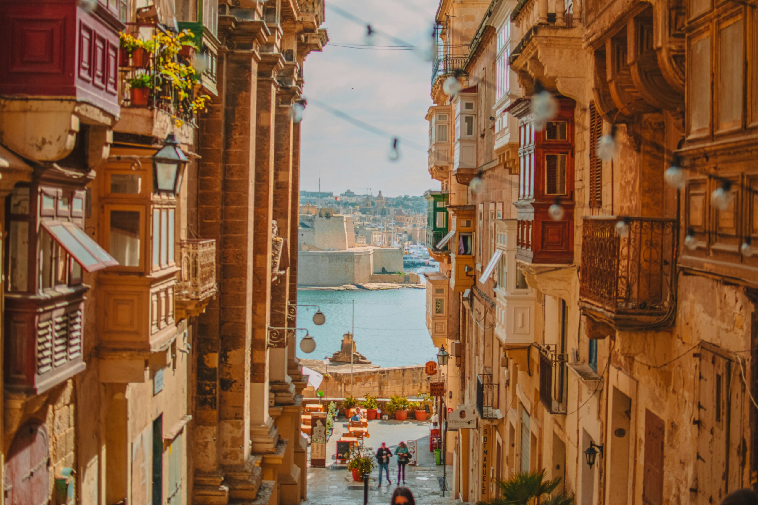 Steep historic street in Valletta, Malta overlooking the harbor with tall buildings and stone steps.