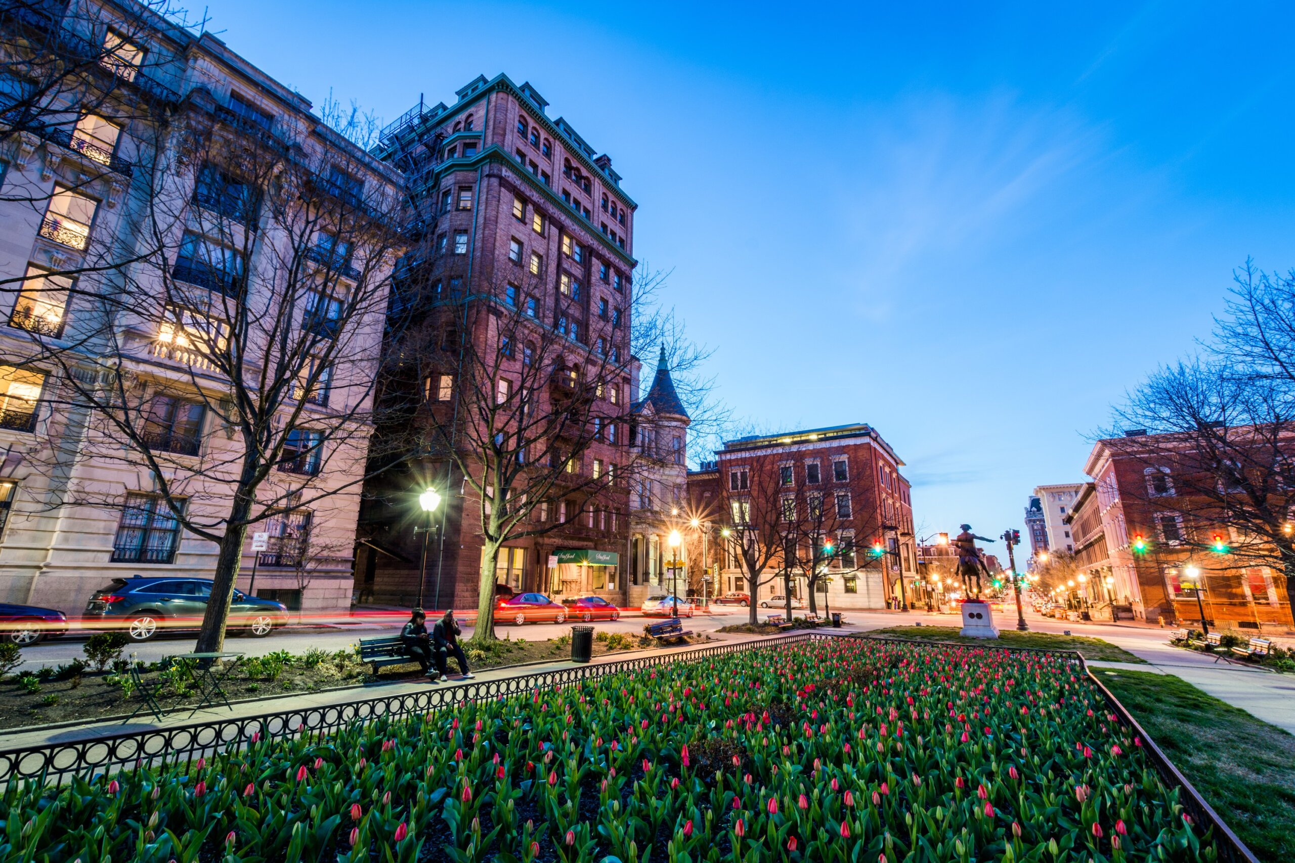 Downtown city street at dusk with historic buildings and a park