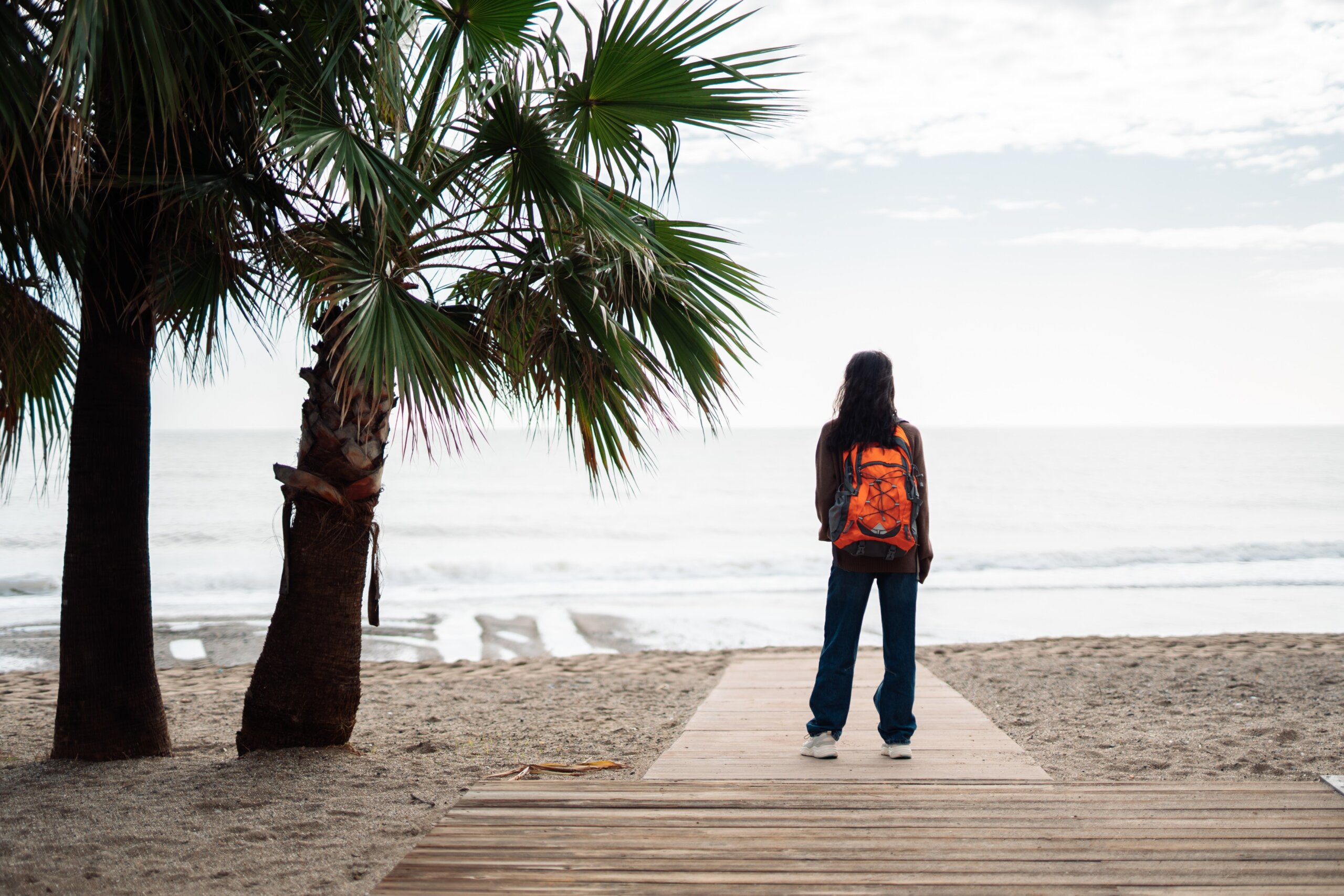 Traveler with backpack at the beach representing travel trends 2026 and 2026 travel changes