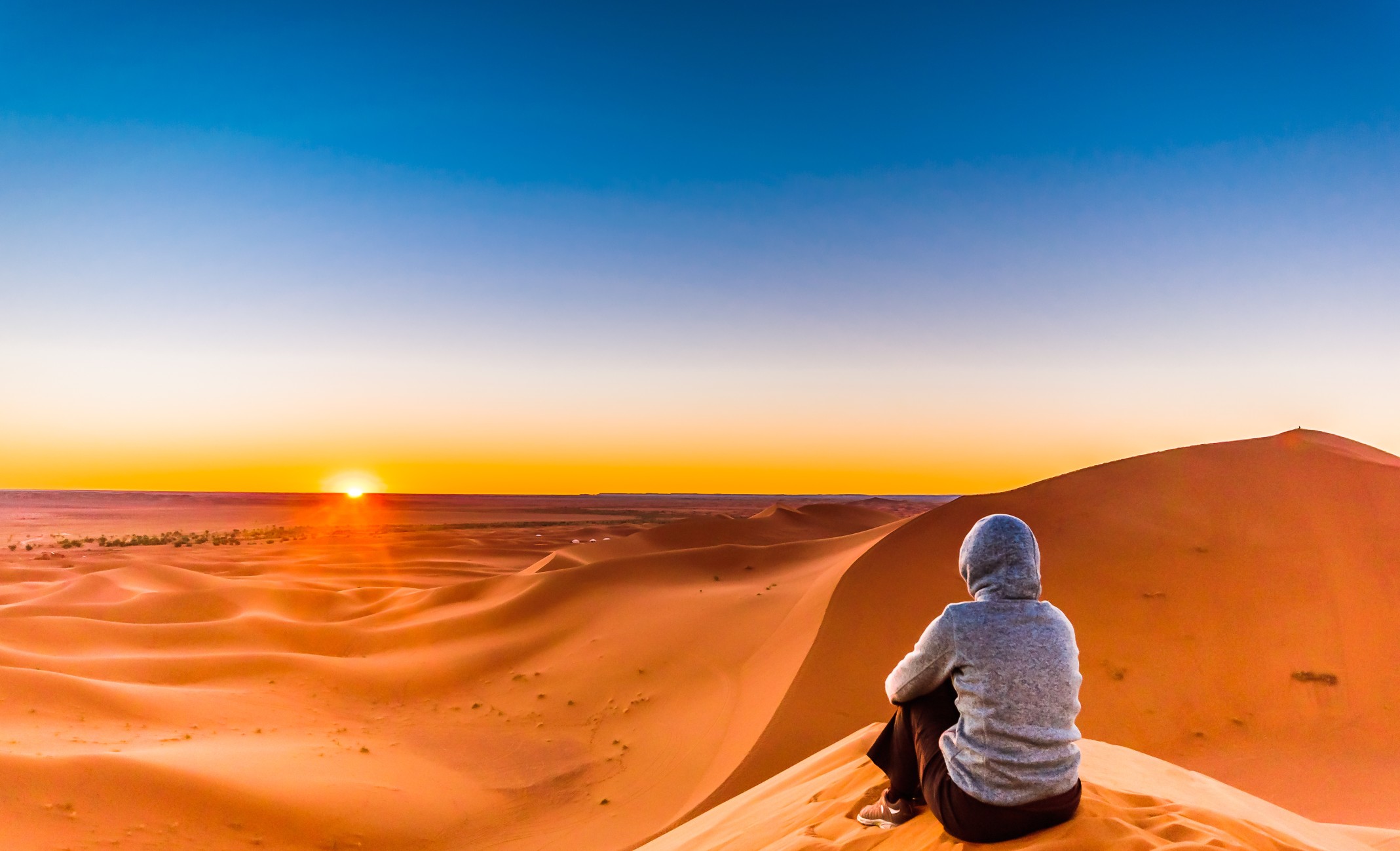 Woman enjoying sunrise in the Sahara Desert next to M'hamid in Morocco
