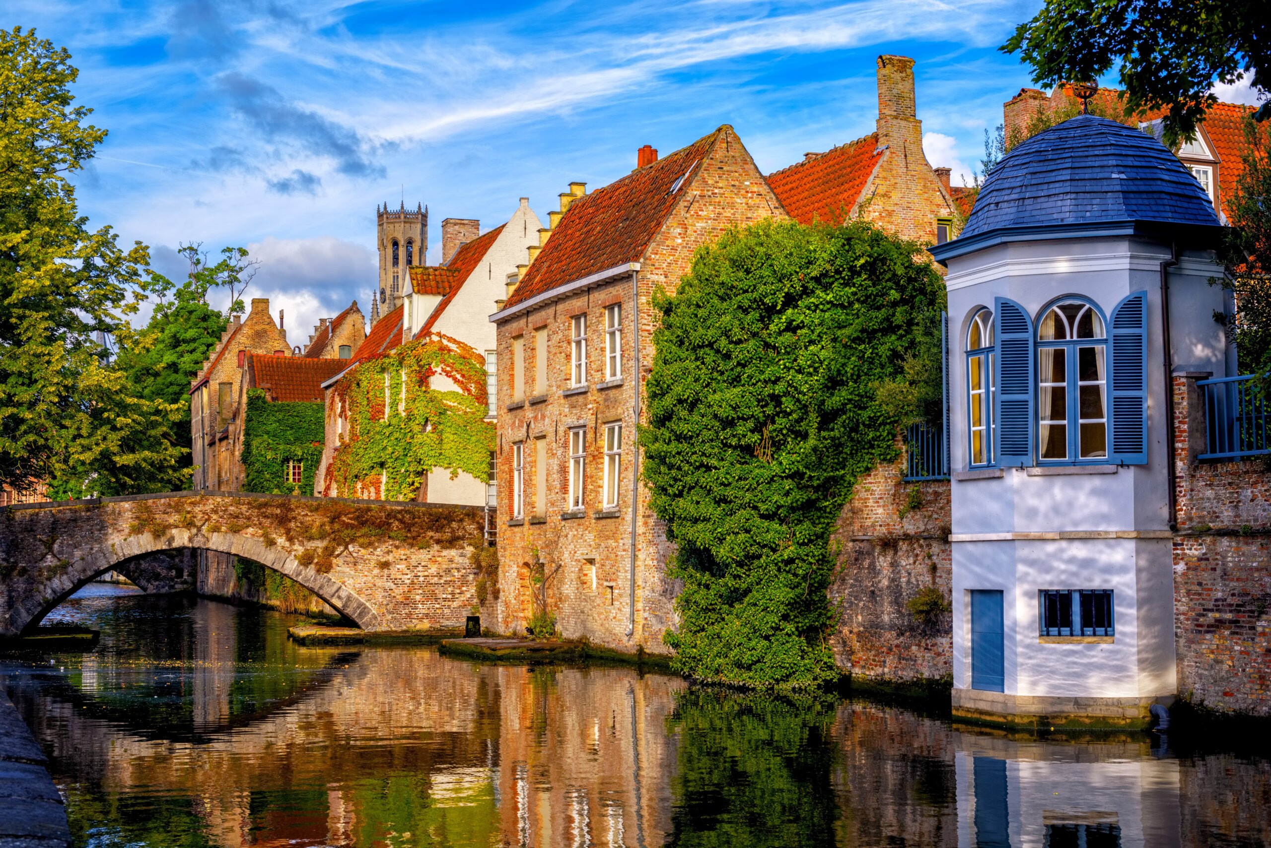 Historic canal in Bruges, Belgium, during shoulder season travel with fewer crowds and calm water reflections