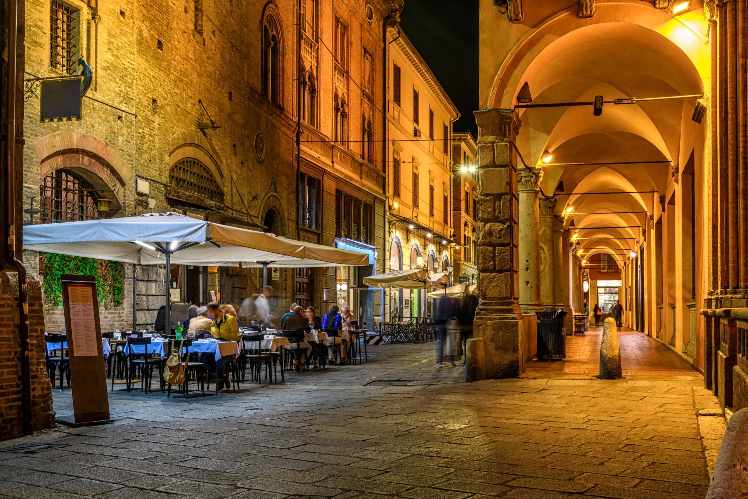 Old narrow street with arcade in Bologna, Emilia Romagna, Italy. Night cityscape of Bologna.