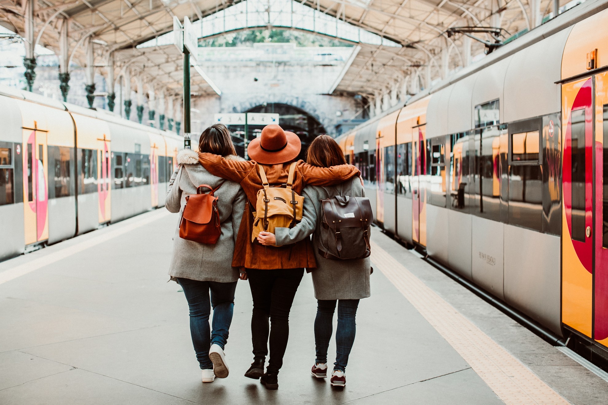 Three best friends walking together at a train station for a Galentine’s Day getaway