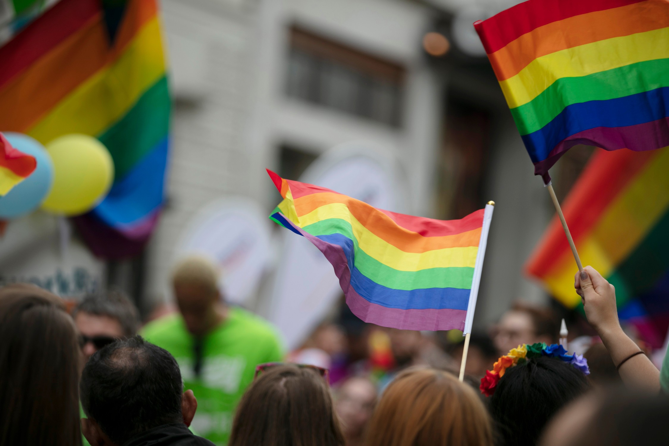Gay pride, LGBTQ rainbow flags being waved in the air at a pride event