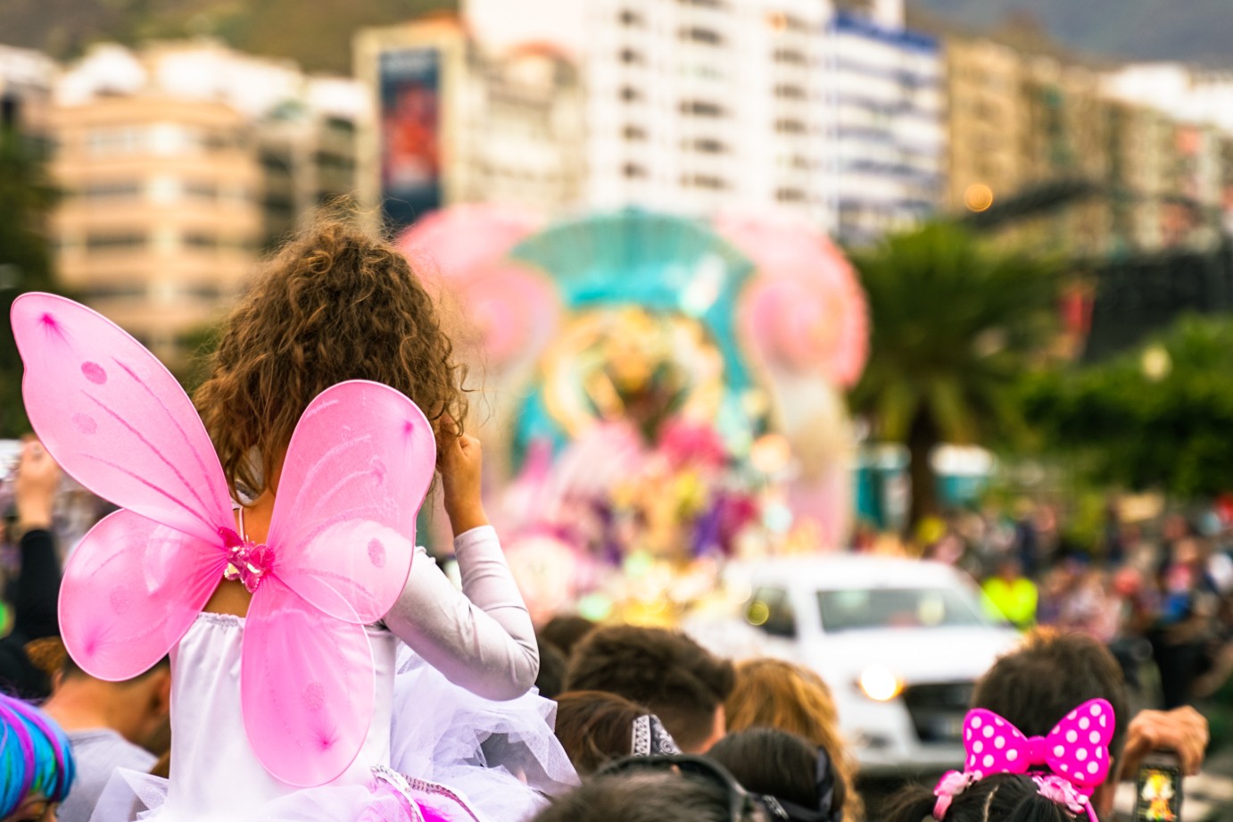 People looking at the carnival party. Pretty girl dressed as a pink angel in a carnival party. Defocused background - Image
