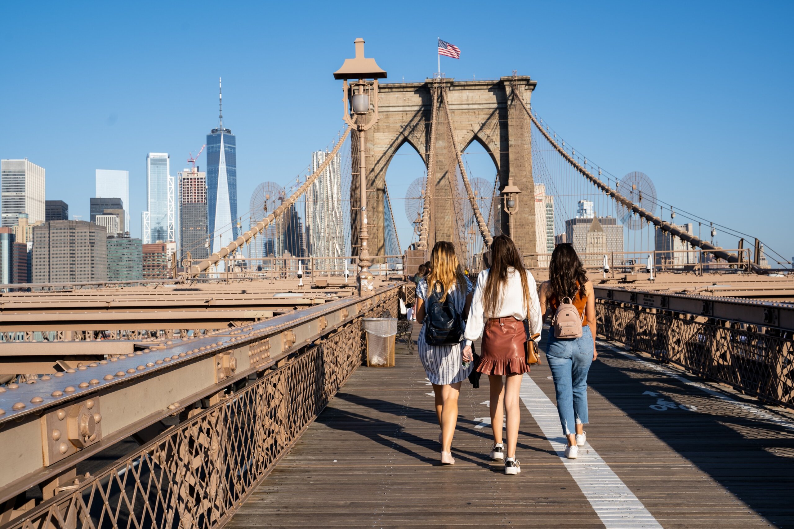 Tourists walking across the Brooklyn Bridge in New York City, reflecting international travel advisories and U.S. travel warnings for visitors