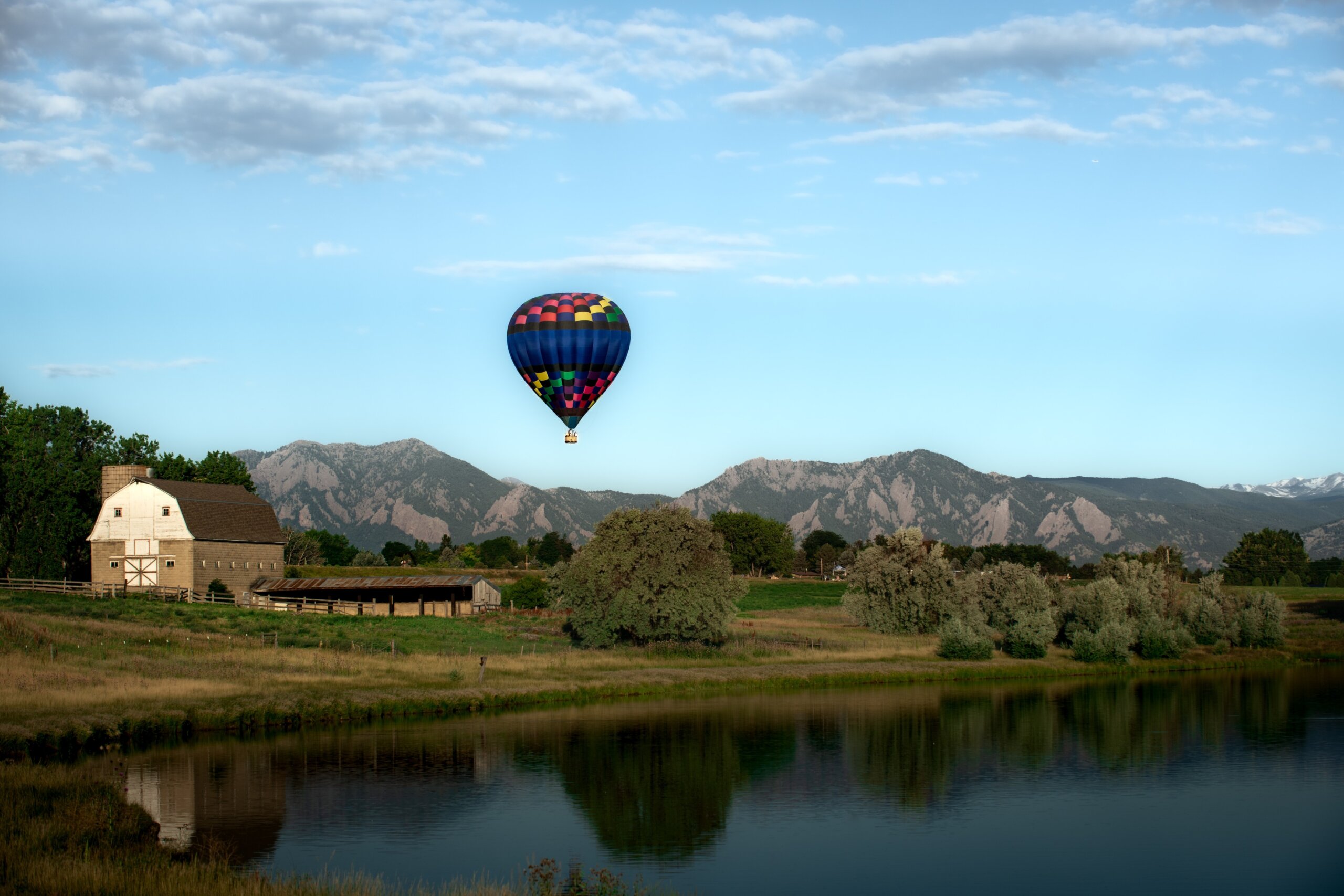A hot air balloon rise above a barn and the Flatirons near Boulder, Colorado
