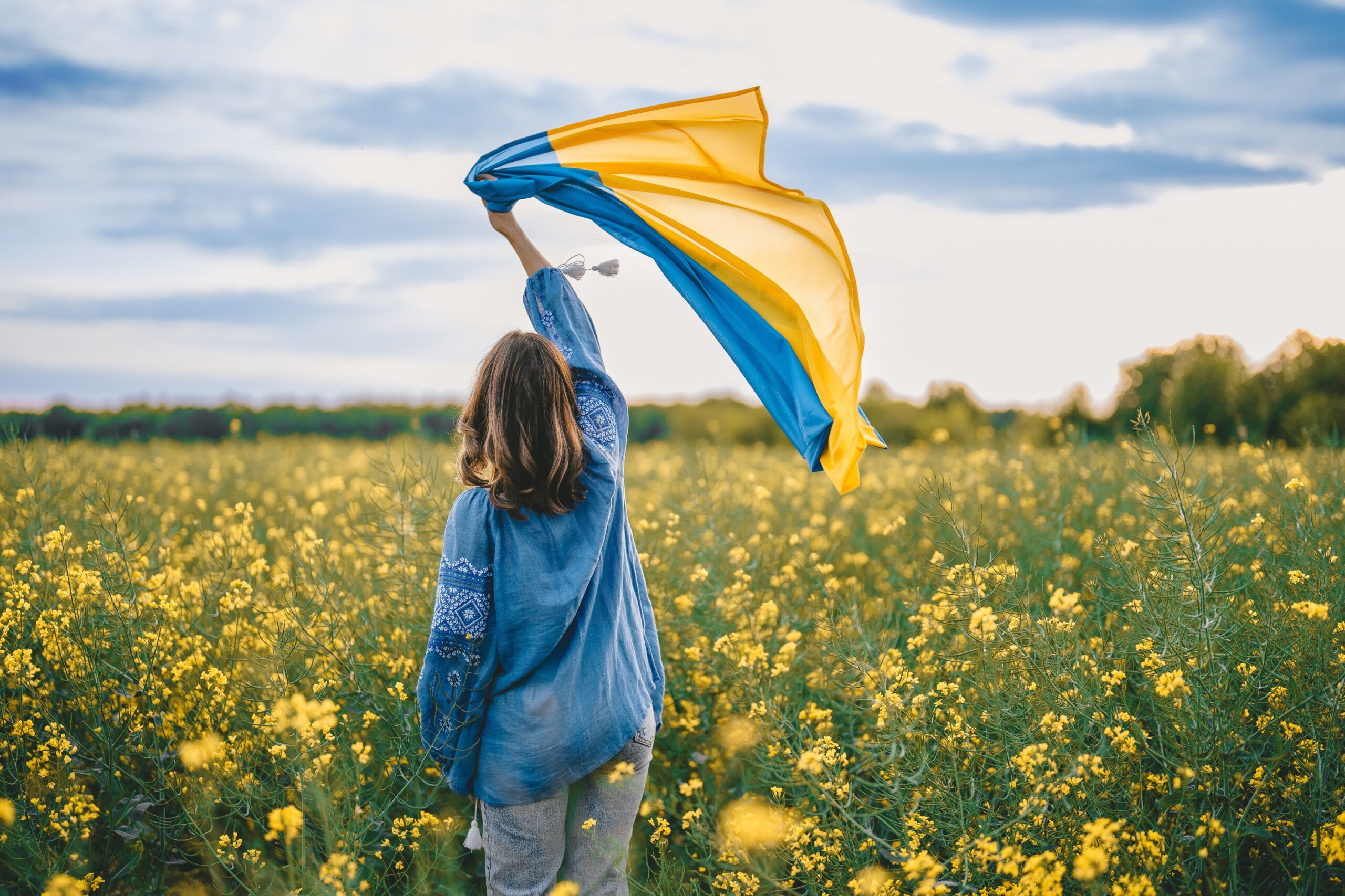Person holding a blue and yellow flag in a field representing travel safety awareness