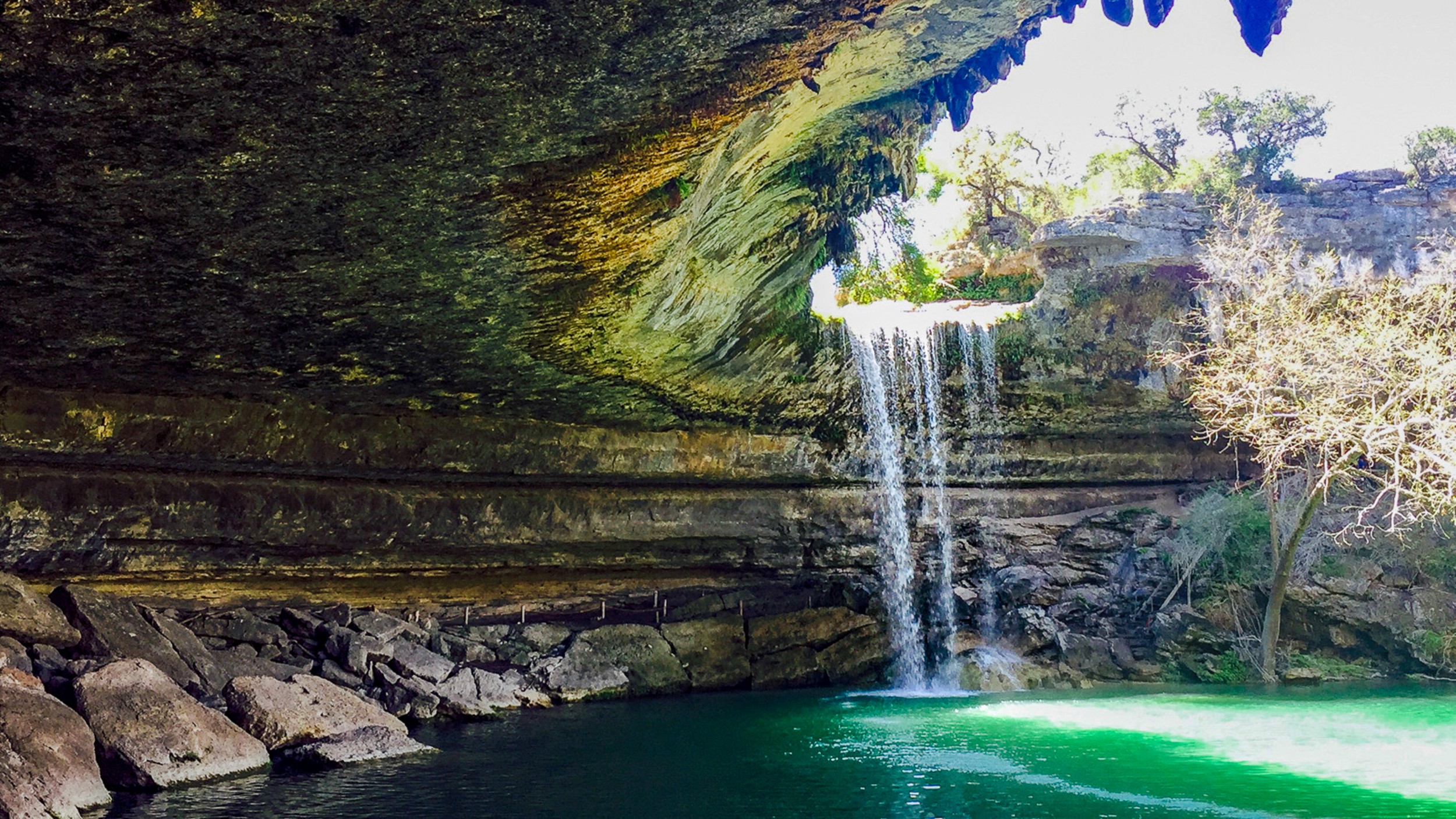 Hamilton Pool Preserve in Austin, Texas with a waterfall and turquoise water beneath a limestone overhang