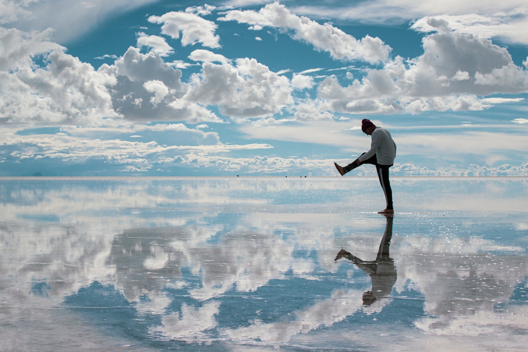 Traveler walking on a mirror-like salt flat representing the most unusual places on Earth