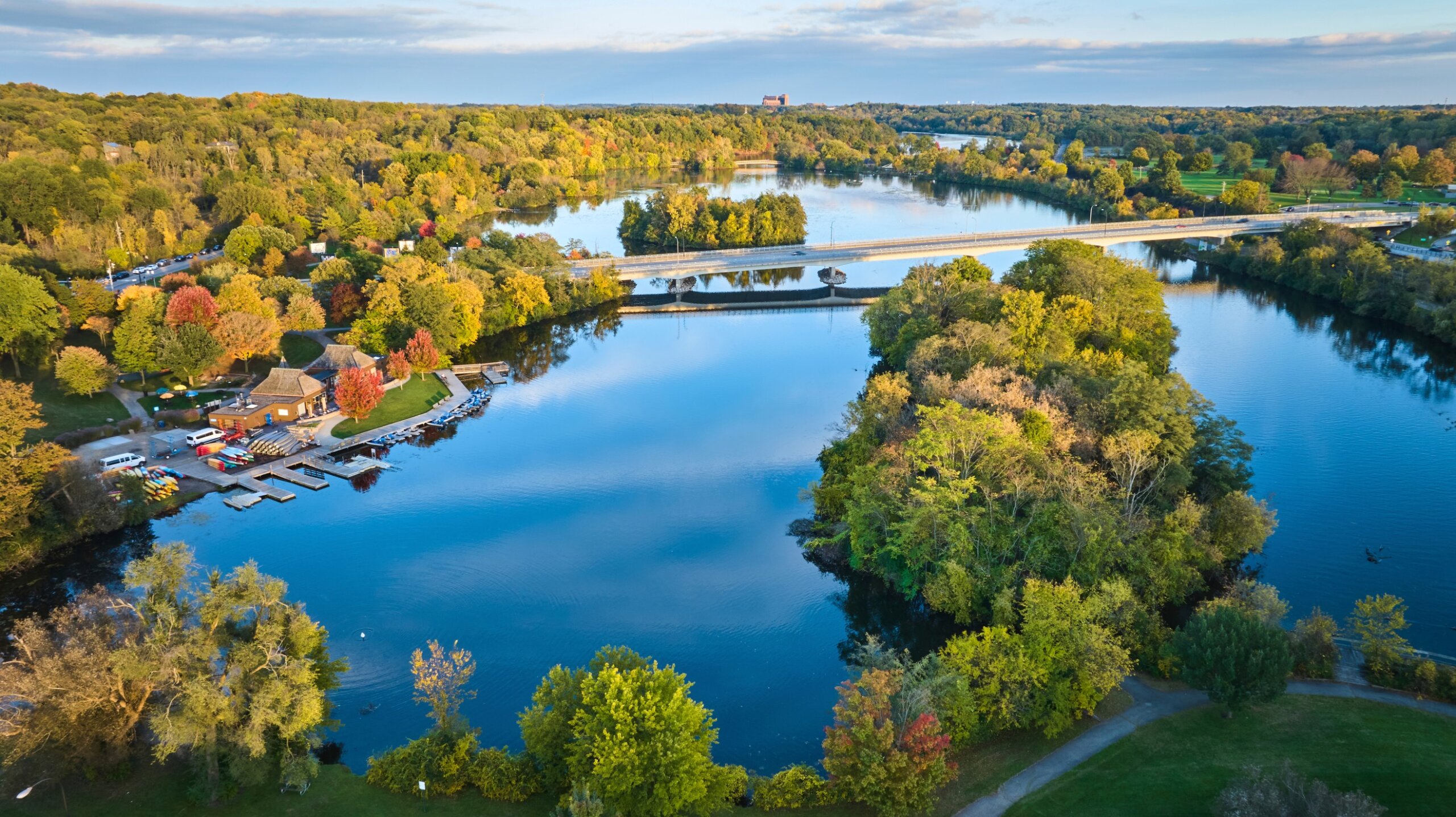 Aerial Autumn Glow Over Kayak-Lined Park and Bridge, Gallup Park, Michigan
