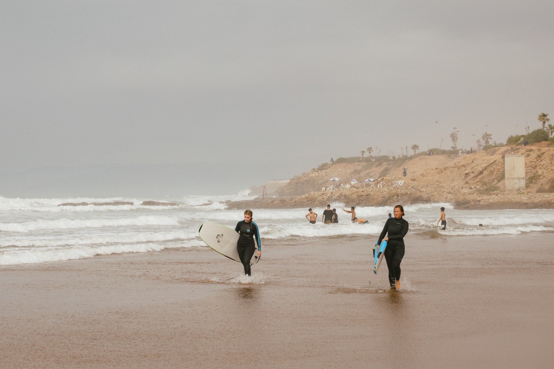 Surfers walking on the beach in Awrir, a Moroccan surf town near Taghazout