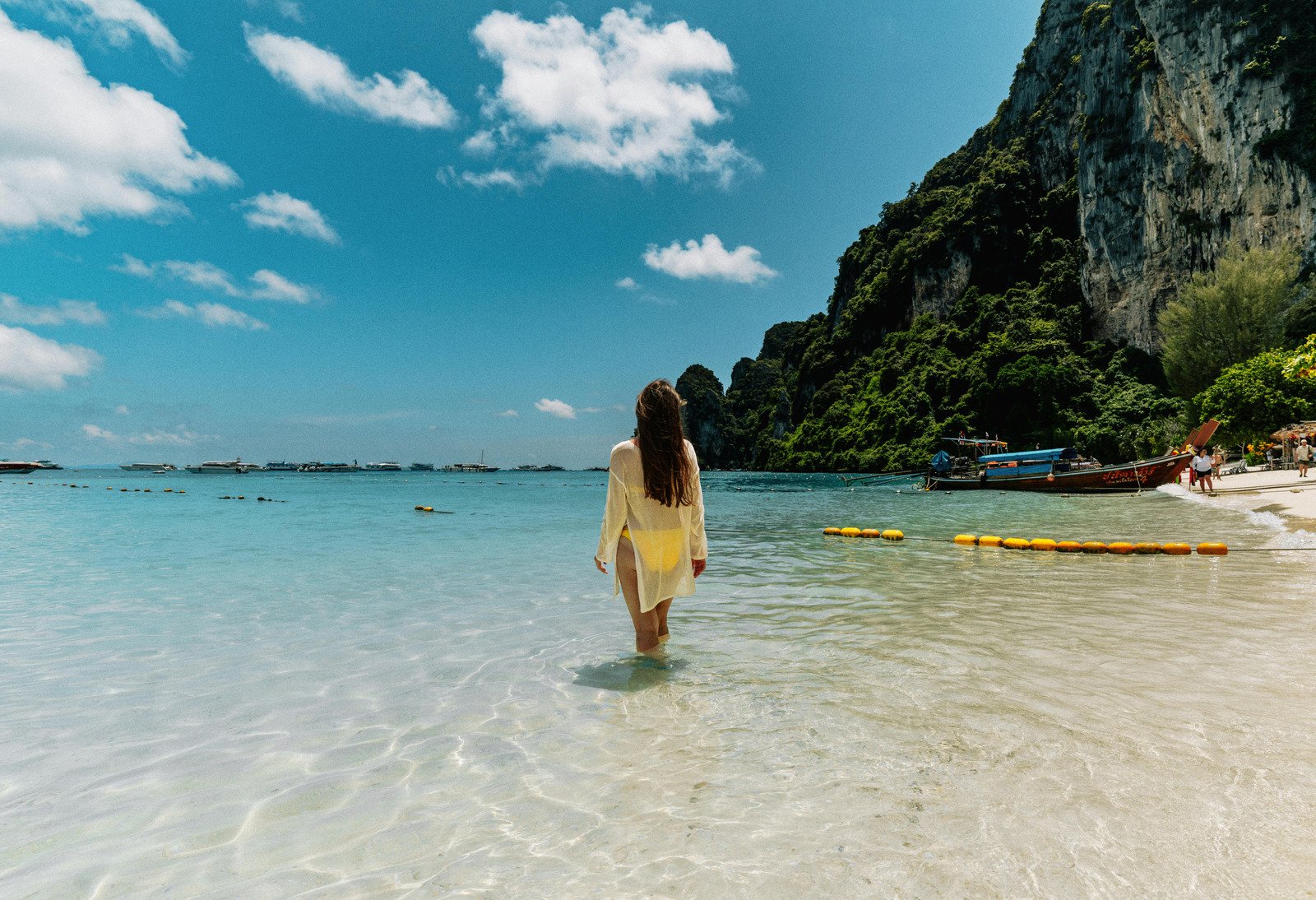 Traveler wading into clear ocean near a cliff, representing mini-retirements and mini-retirement travel for burnout recovery