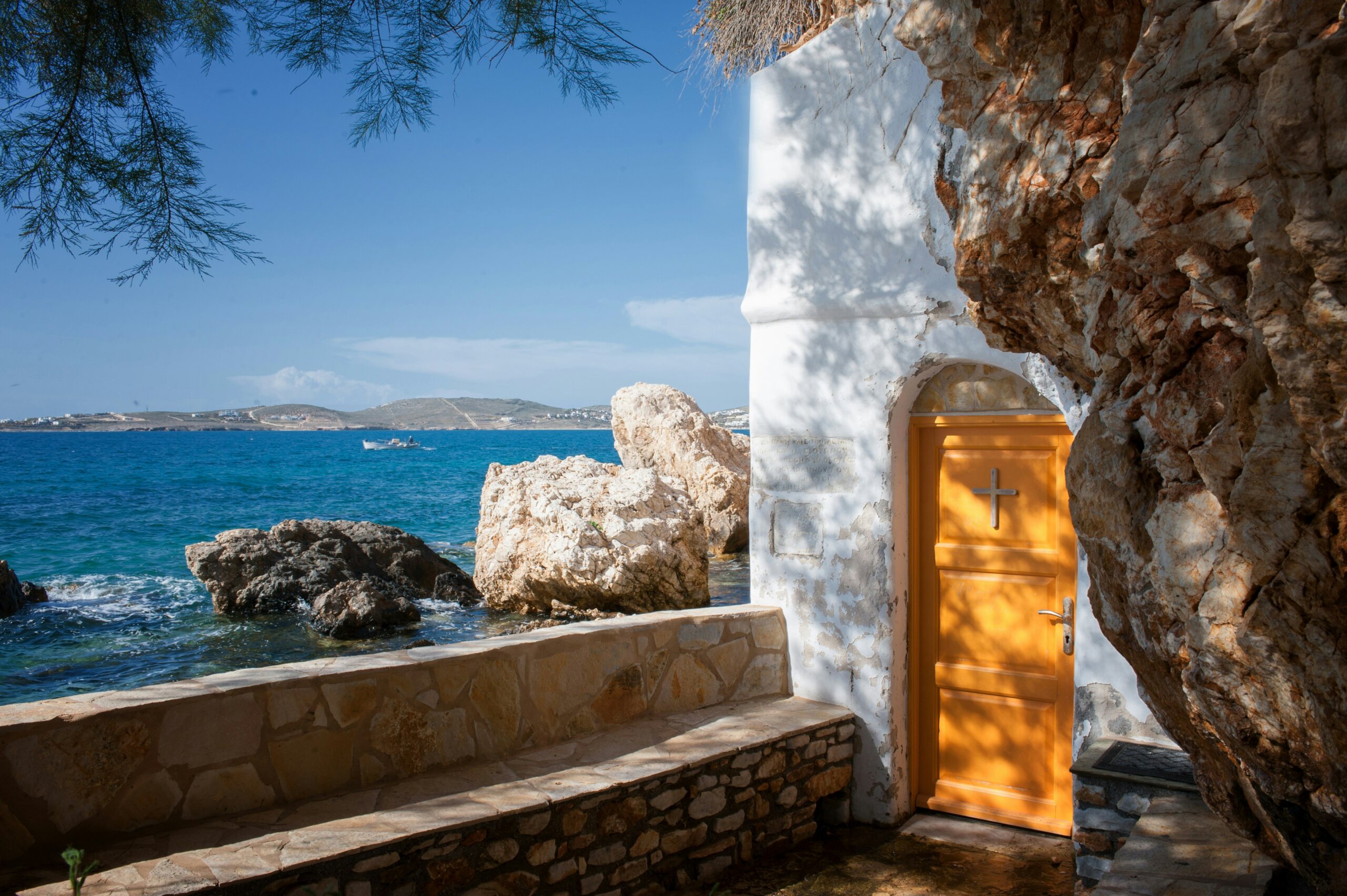 Seaside chapel carved into stone along the Greek coast, representing slow travel experiences and sensory journeys