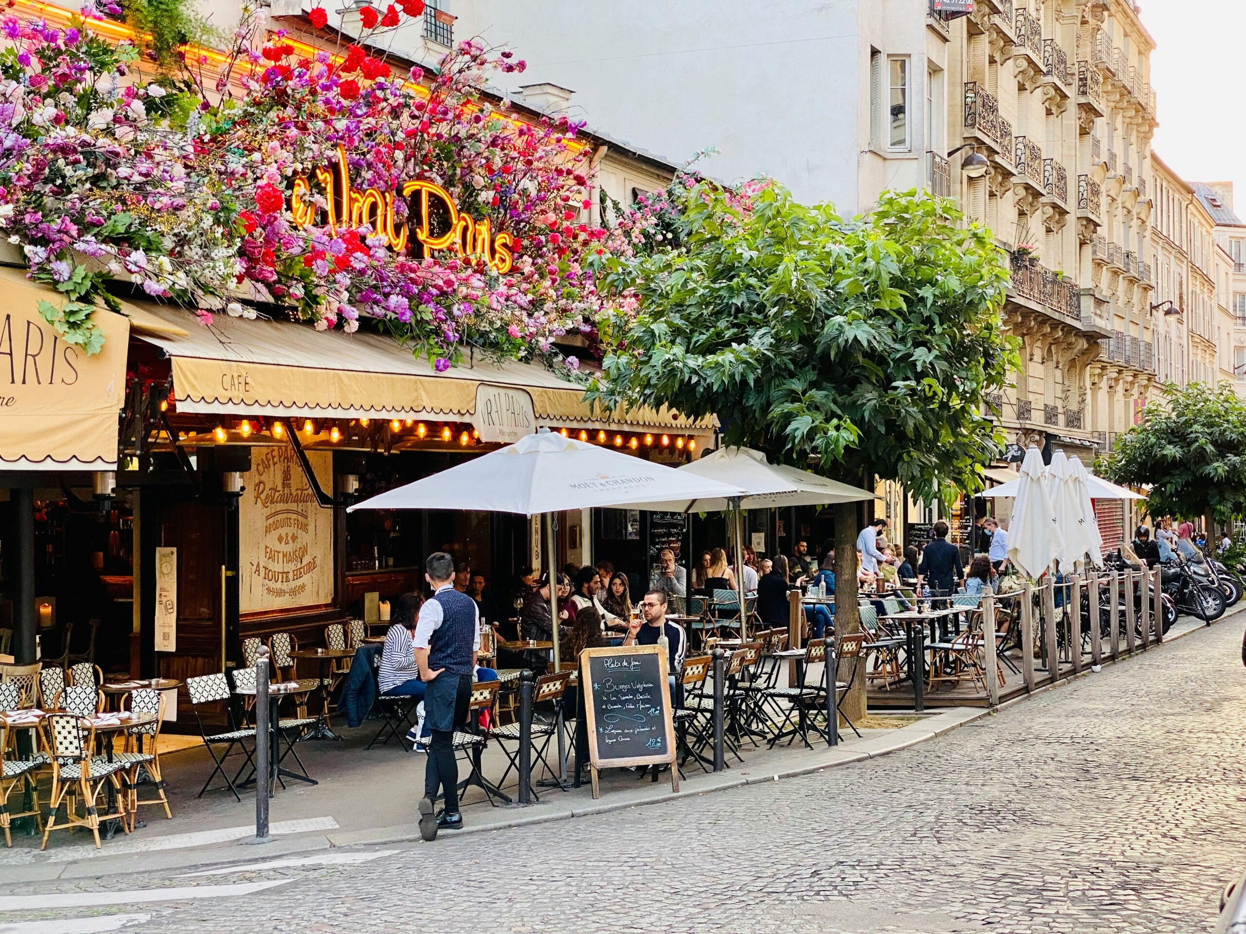 Paris street café with outdoor tables and umbrellas on a cobblestone road
