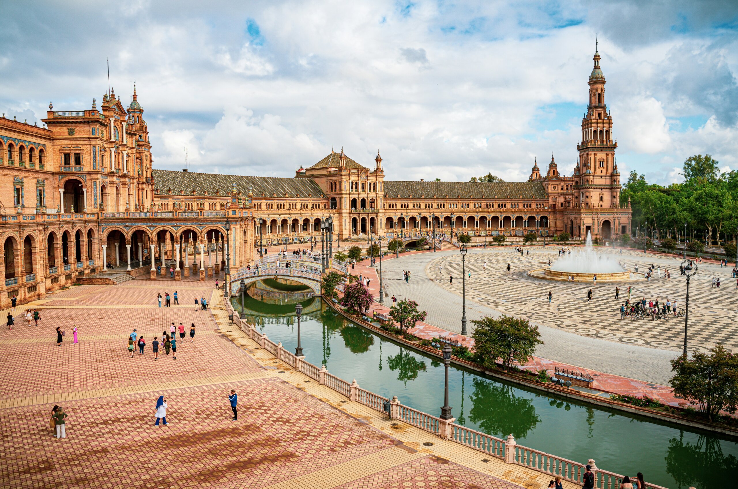 Plaza de Espana in Seville Spain with canal fountain and tourists under blue sky winter destination