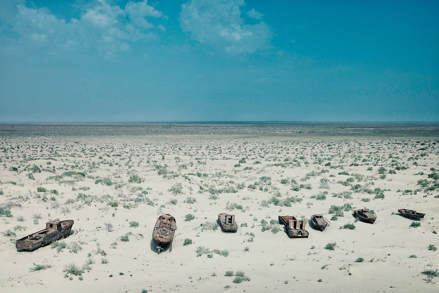 abandoned boats rusting away in the sand at the once blooming sea port