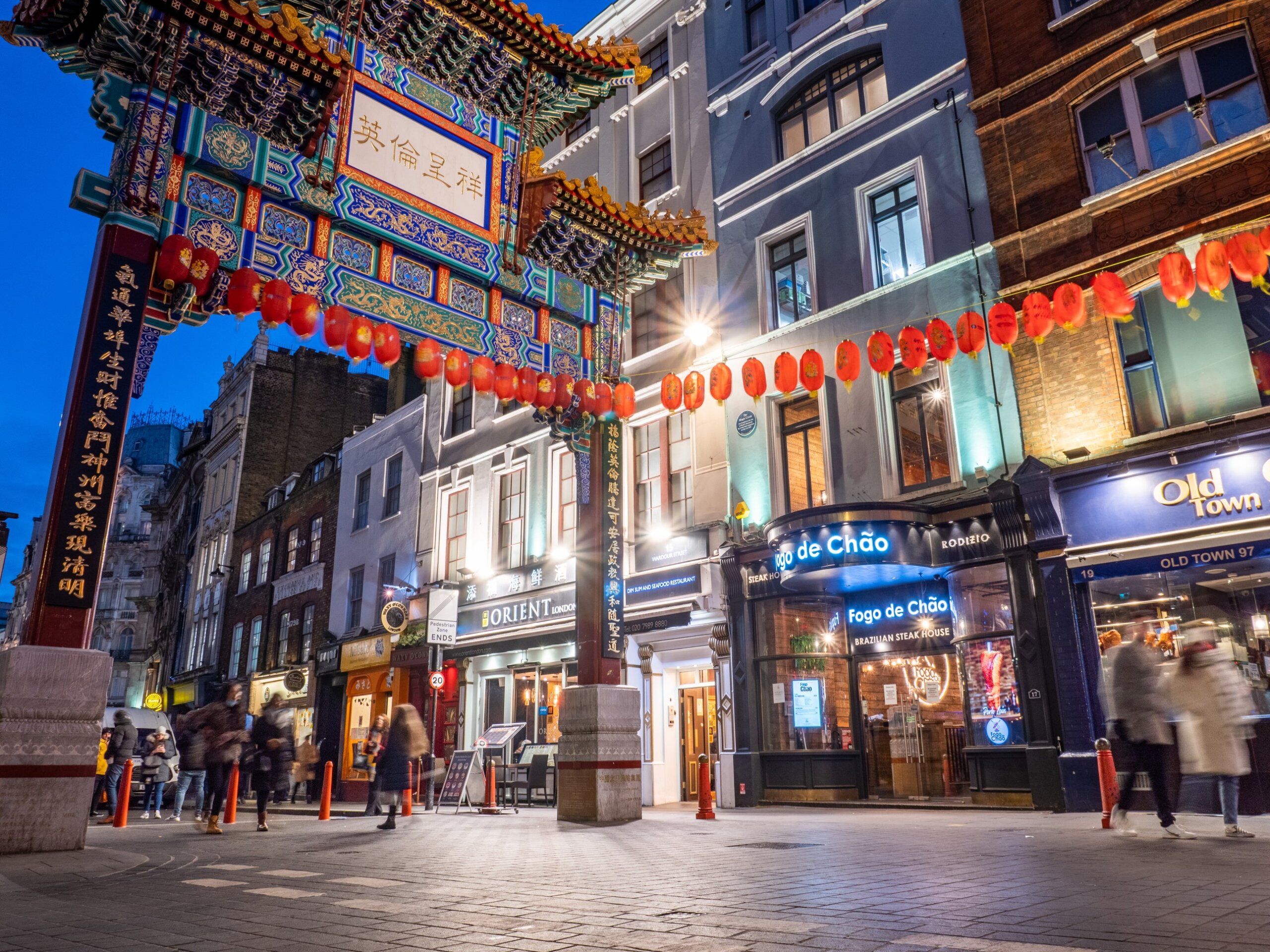 Dragon Gate, Chinatown, London. A dusk view of tourists passing through the landmark gate in the popular central London shopping and dining district.
