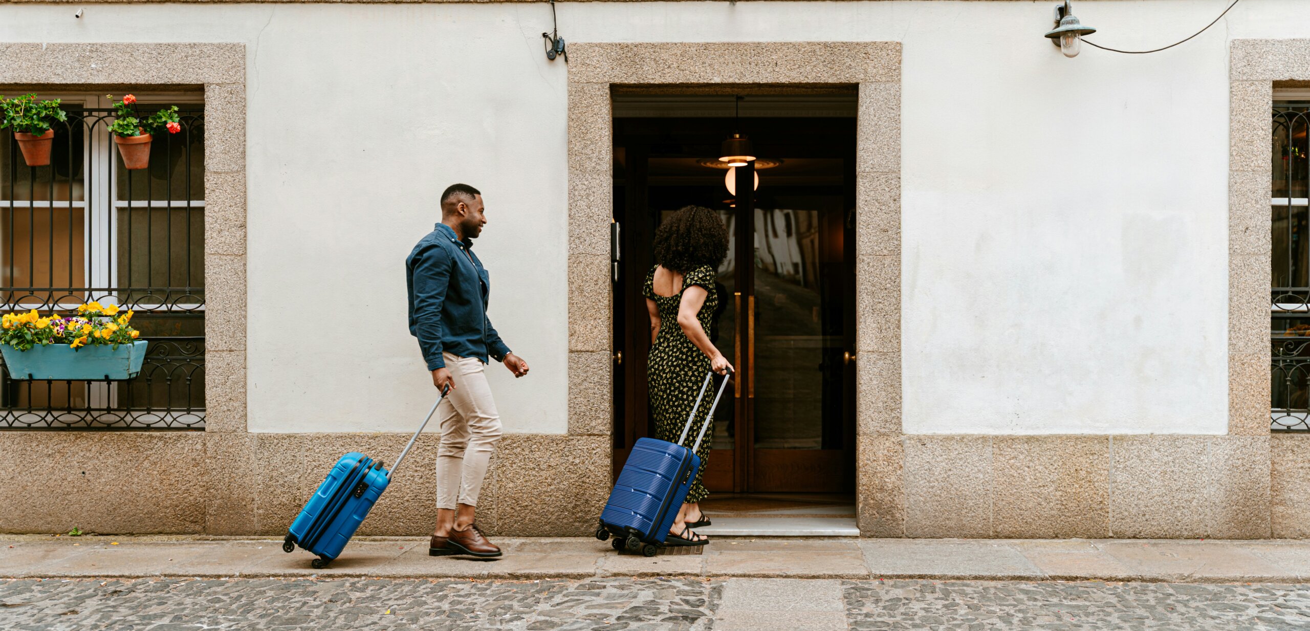Couple rolling suitcases into a hotel