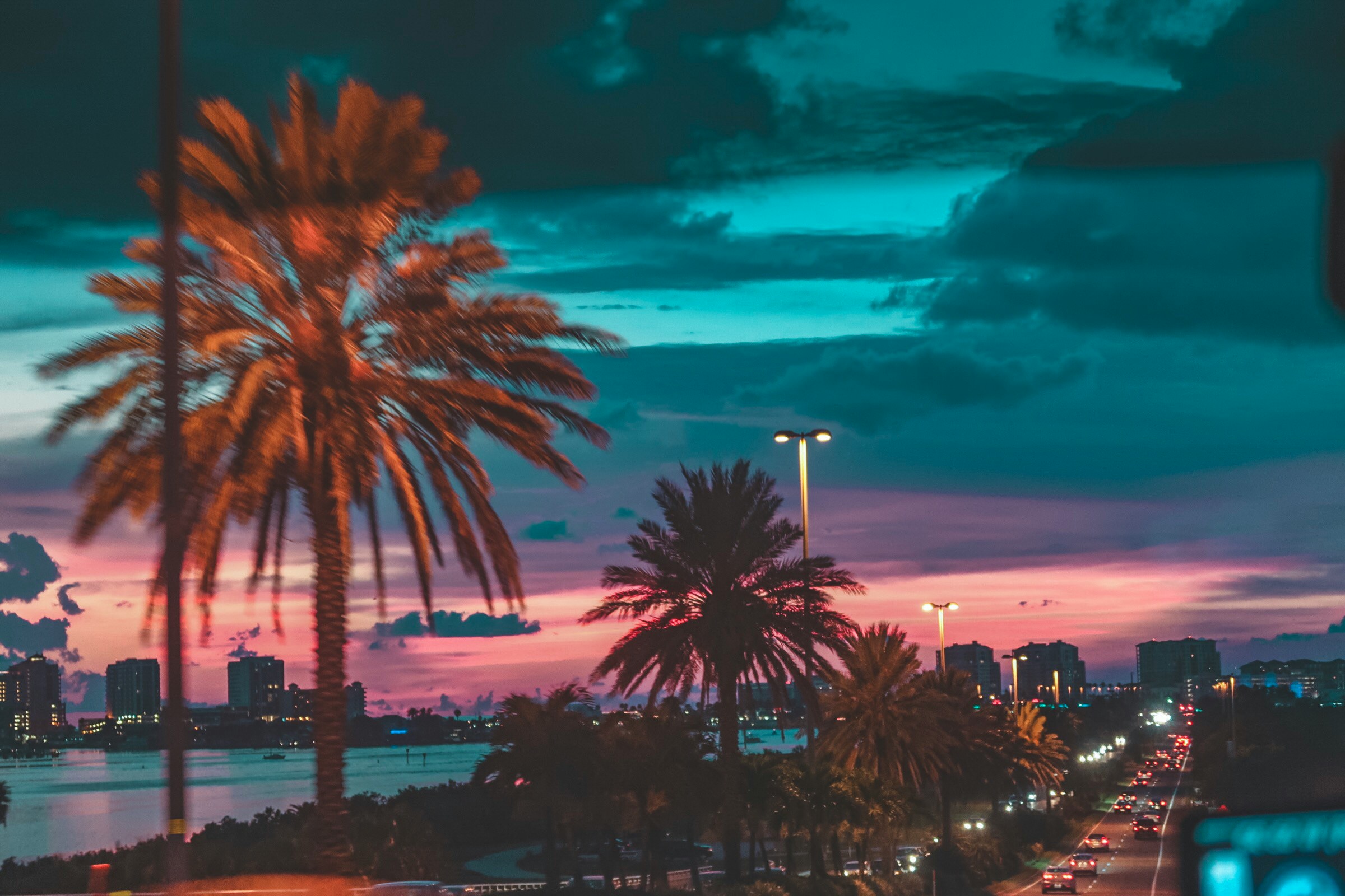 Florida skyline at sunset with palm trees and heavy traffic along waterfront highway