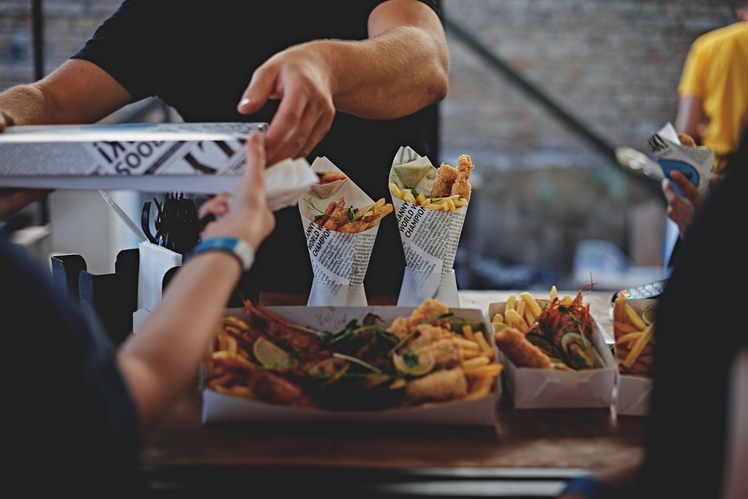 Street food vendor serving fried seafood and fries at a busy outdoor market stall