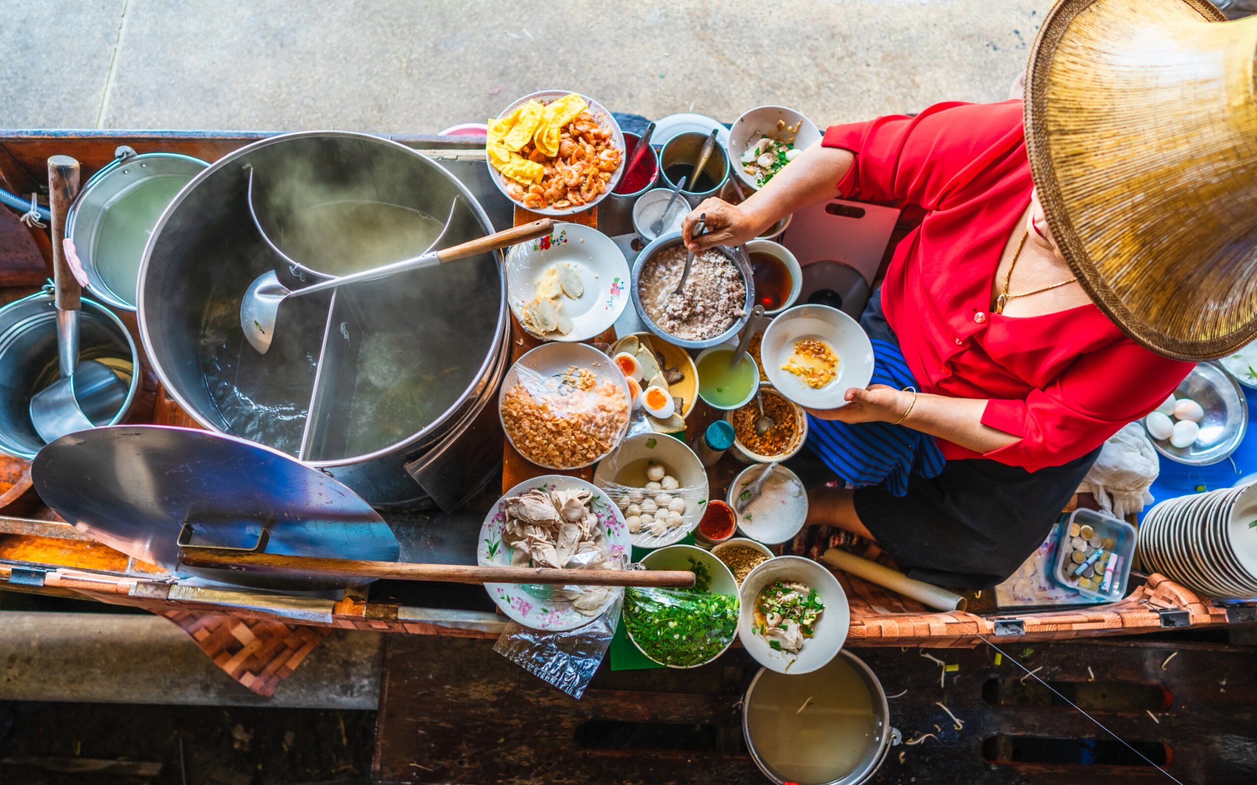 Top view old woman cooking Thai noodle soup Tom Yam style on Thai tradition boat in local floating market, Famous traditional Thai street food for tourist people travel Bangkok Thailand, Tasty Asia