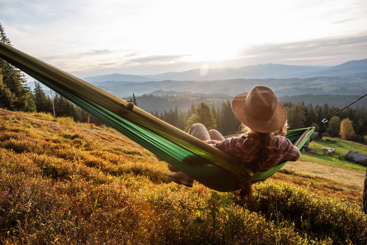 person relaxing in hammock overlooking mountains during slow travel vacation