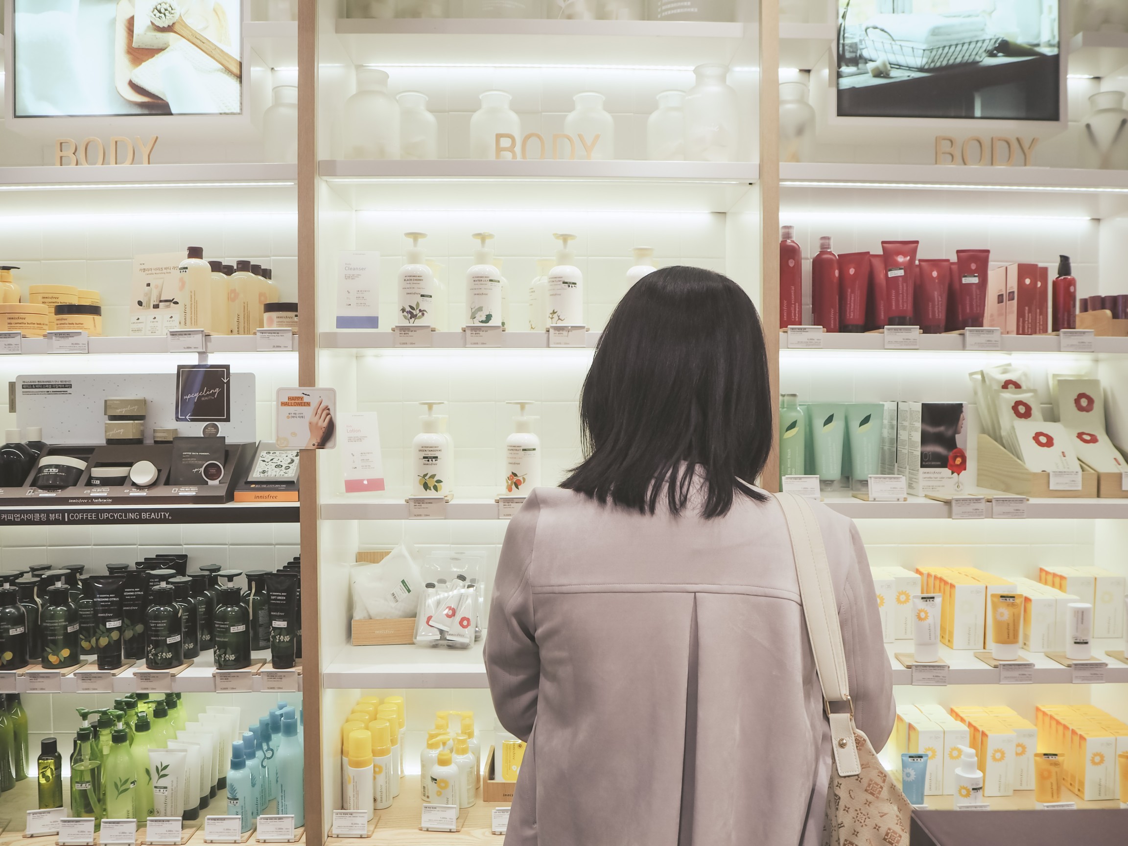 October 2018 - Seoul, South Korea: Young Asian woman standing in front of shelf with skincare products of the South Korean brand Innisfree
