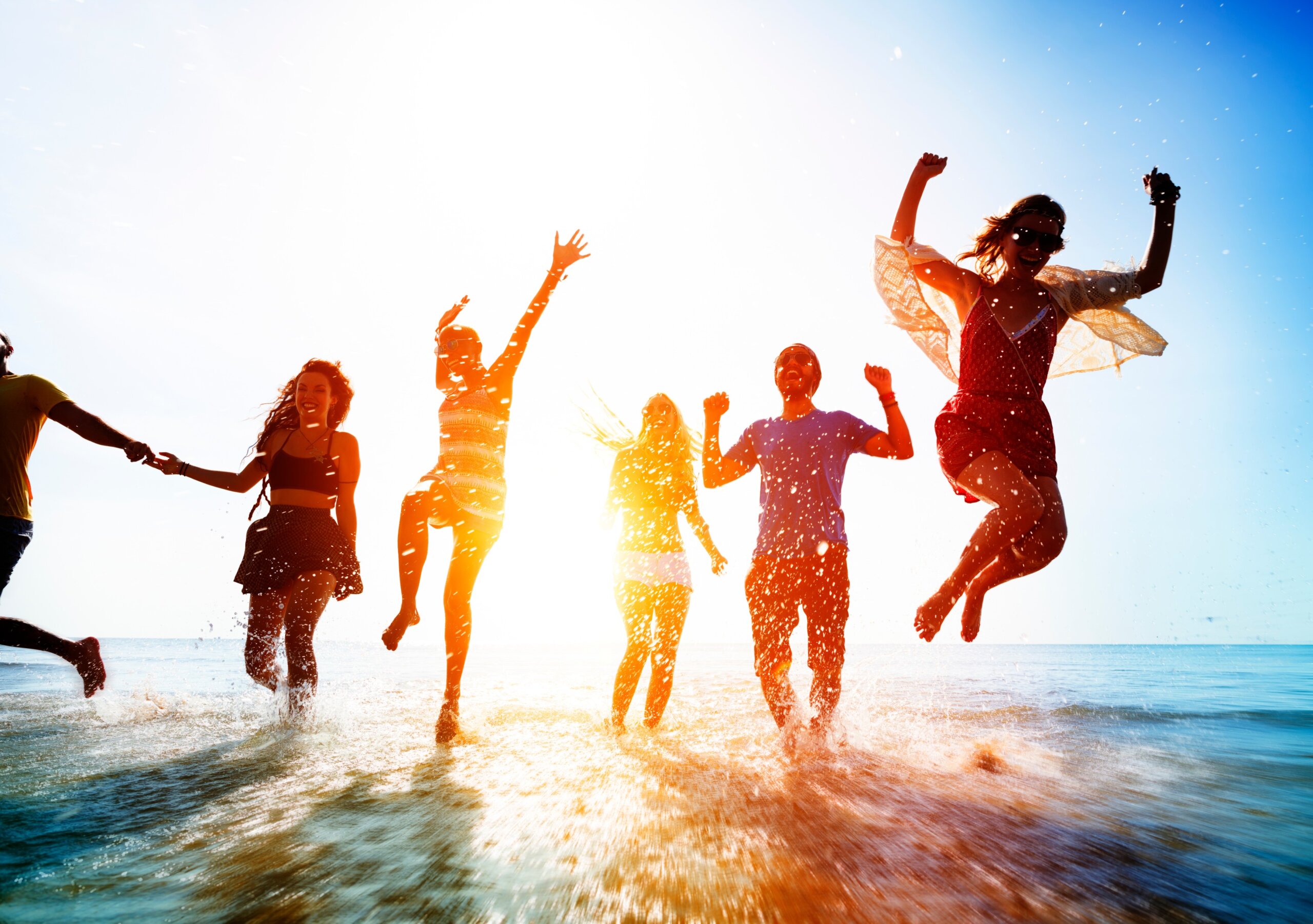 Friends jumping in the ocean at a sunny spring break beach destination