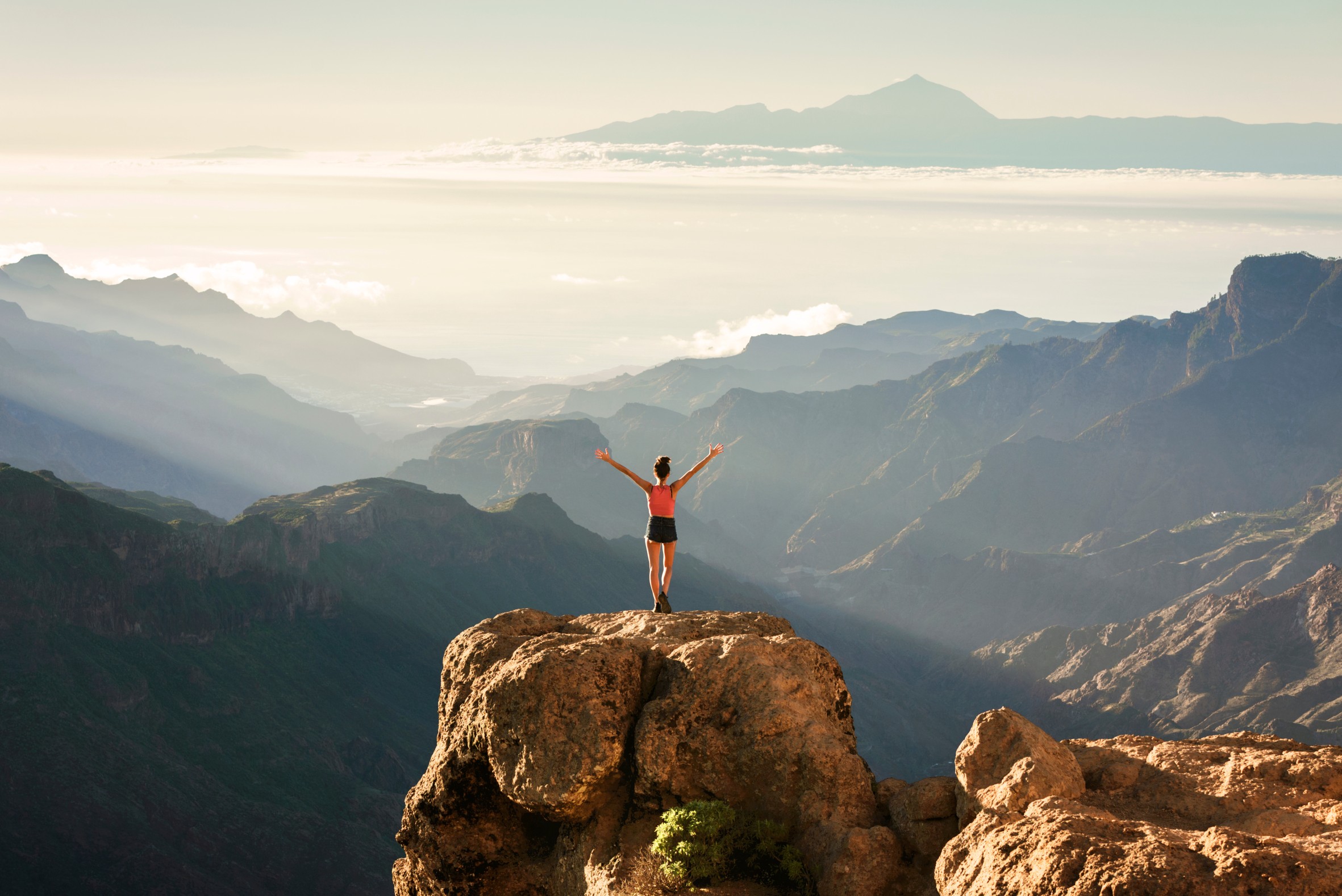 Young hiker girl overlooking the stunning views of Nublo Rural Park and Mount Teide in the distance, Tejeda, Gran Canaria, Canary Islands, Spain
