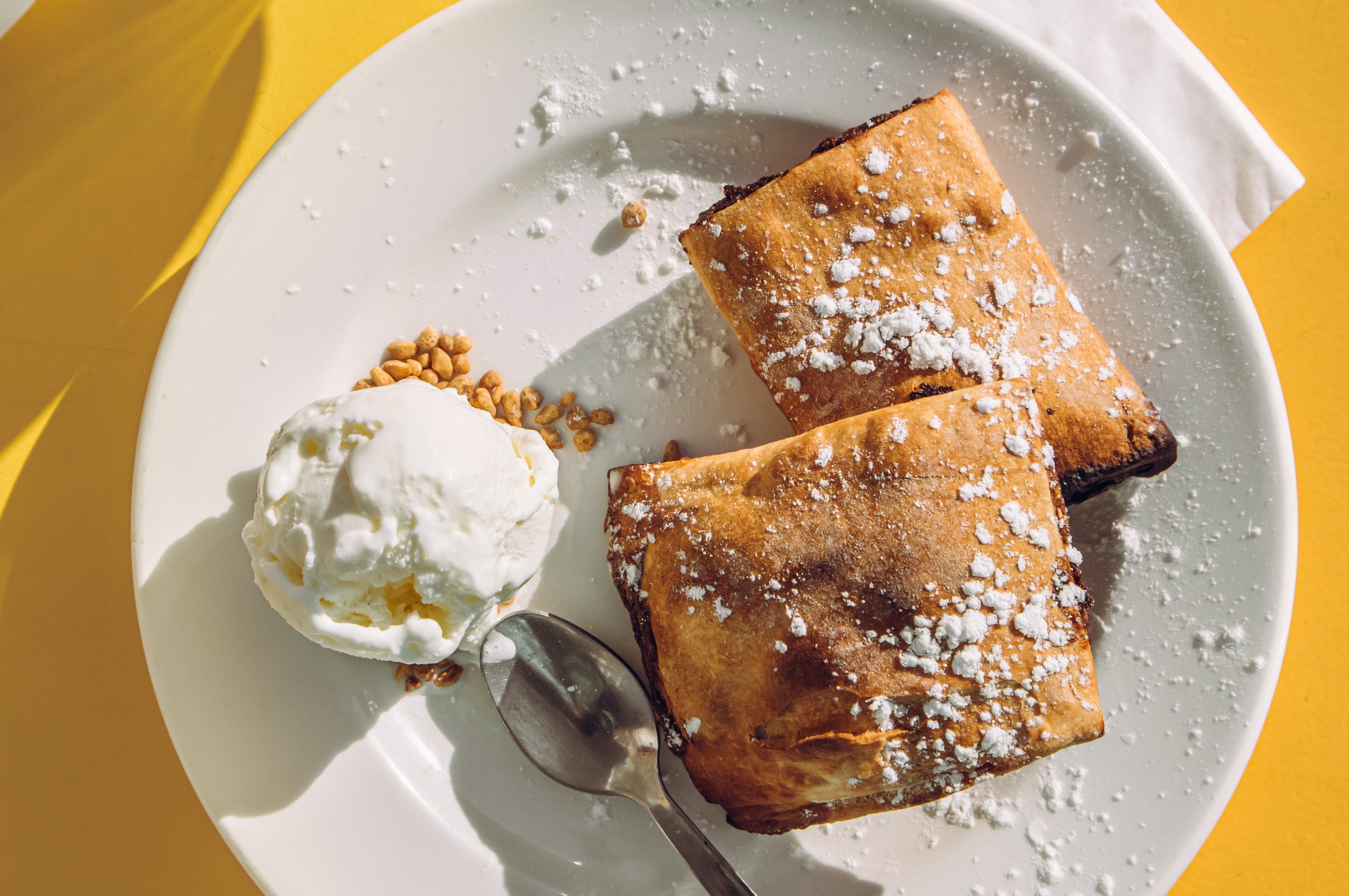 Maltese date filled pastry called Imqaret served with ice cream on plate.
