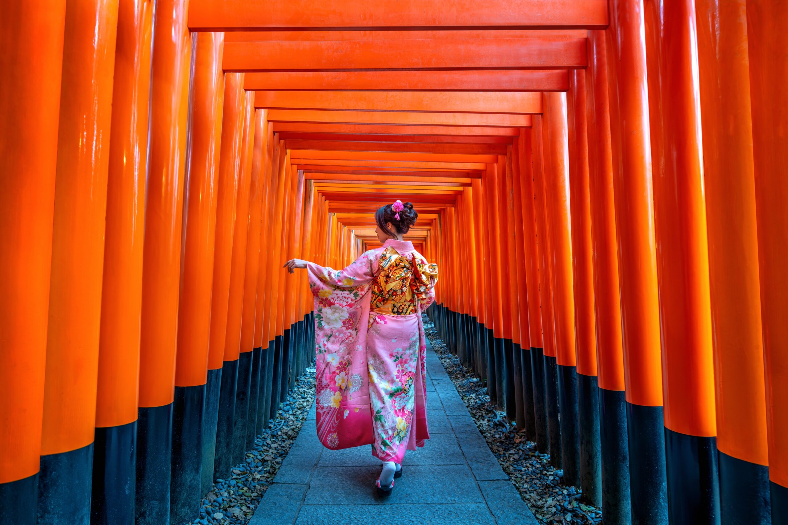 woman walking through torii gates at Fushimi Inari shrine Kyoto Japan