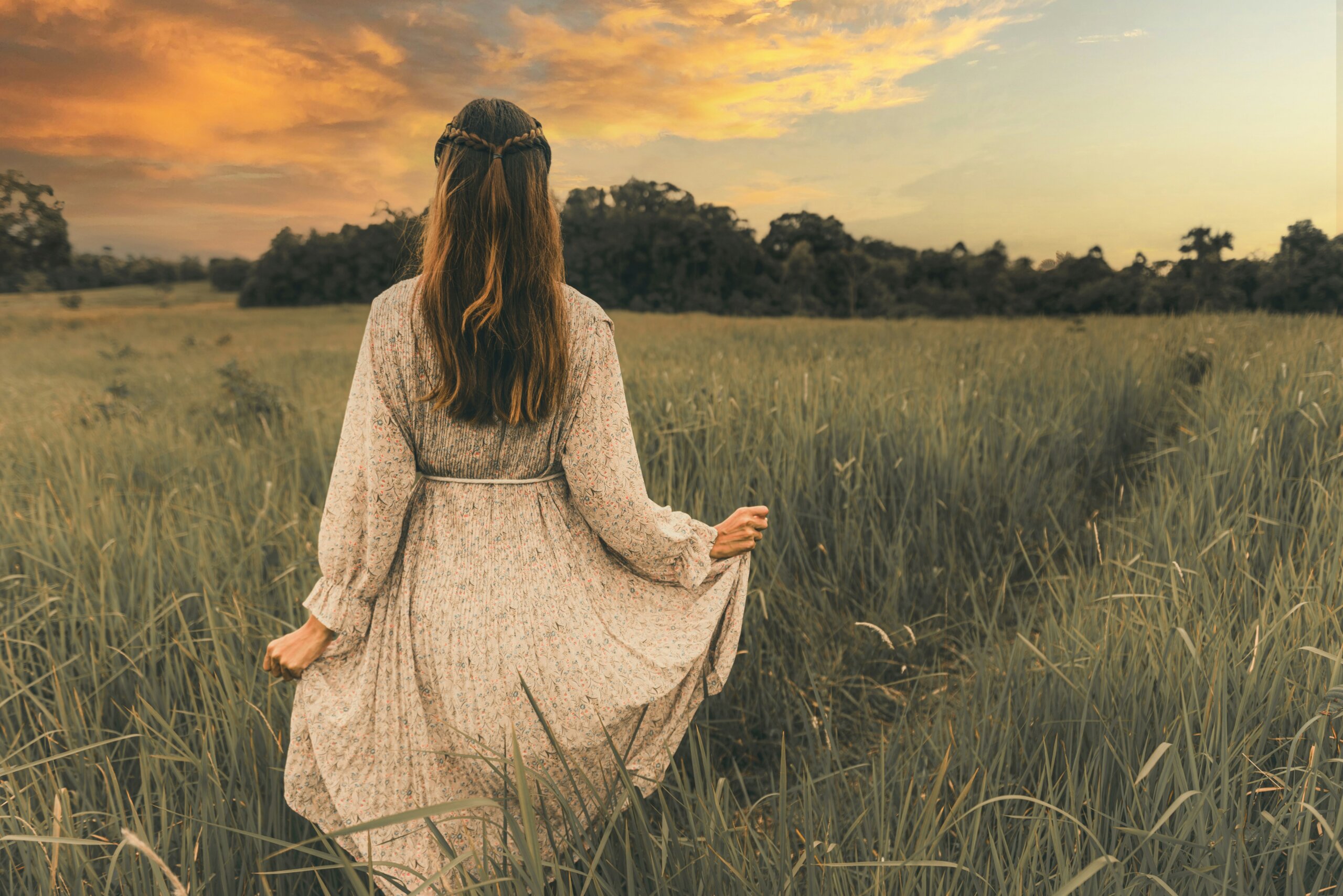Woman walking through a field at sunset representing slow travel