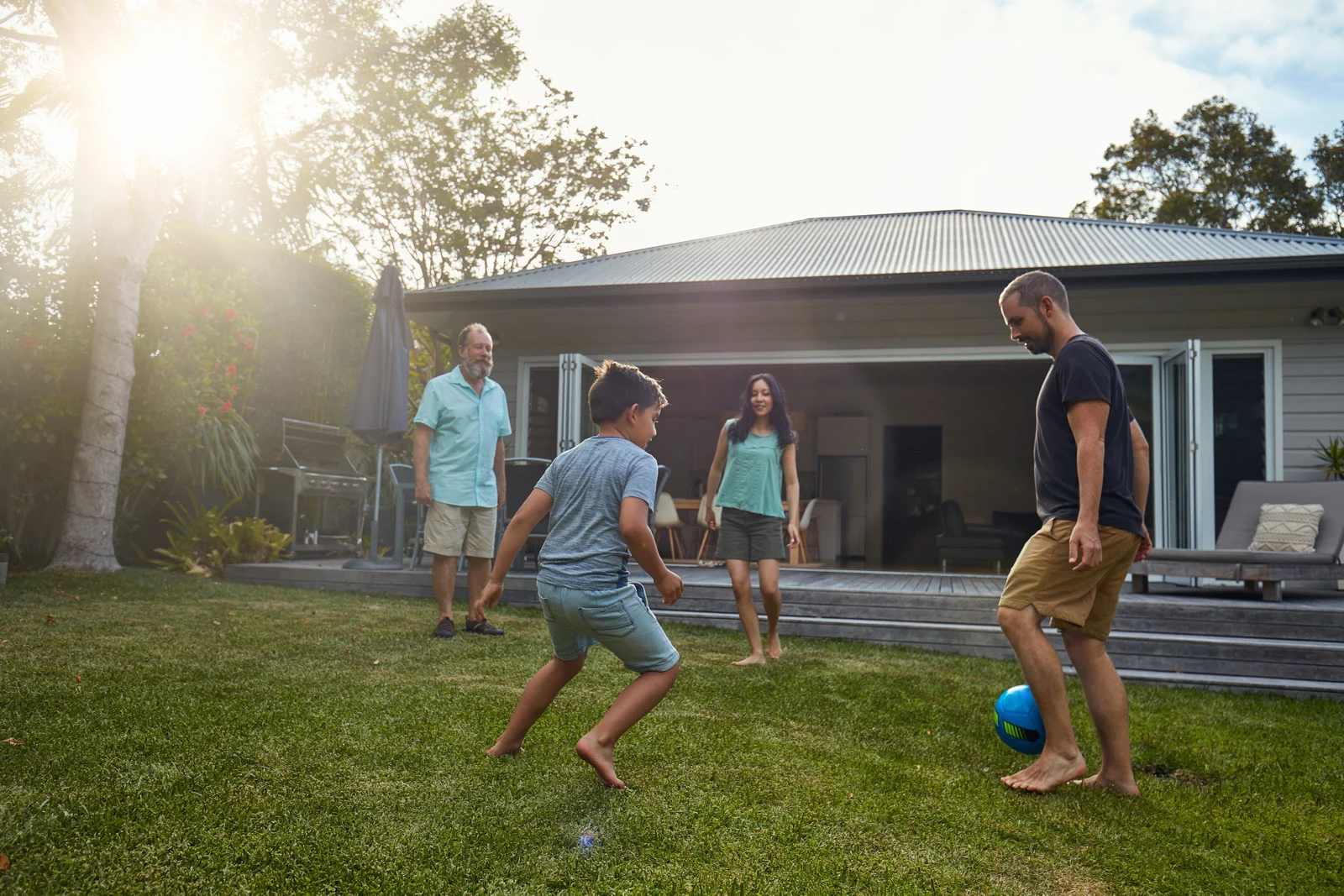 Family playing soccer in backyard of suburban home representing life in small U.S. cities