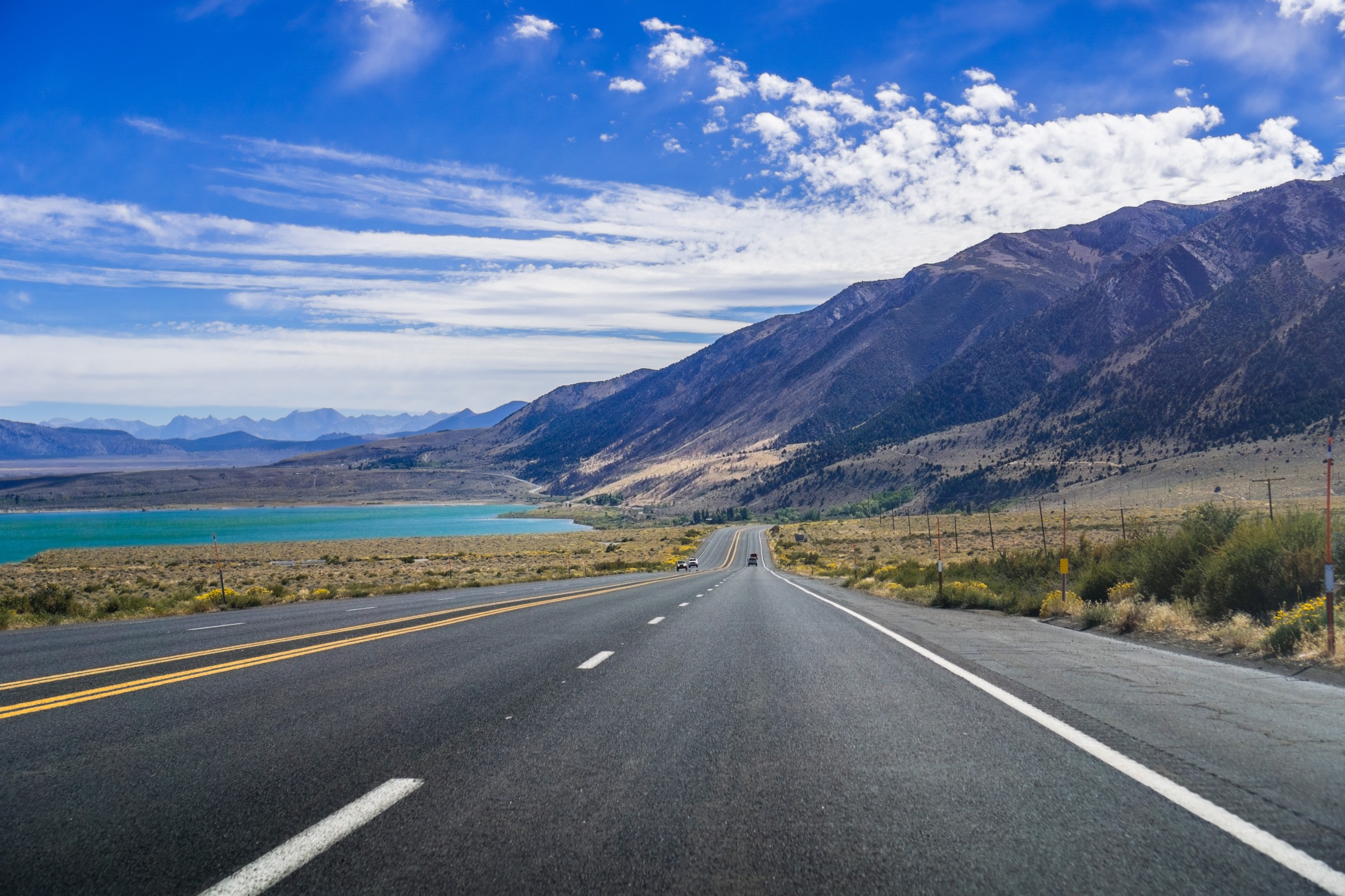 Wide open American highway stretching into a dramatic landscape, representing road trip travel and flight-free adventures