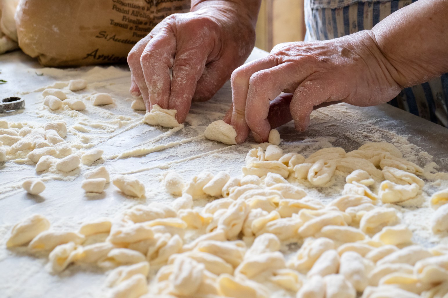 Hands of Italian woman making traditional fresh pasta on a marble table
