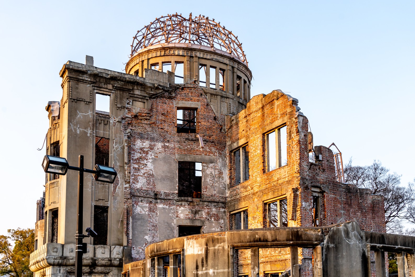 Hiroshima Peace Memorial A-Bomb Dome ruins at golden hour with exposed steel dome frame and damaged brick walls against a clear sky