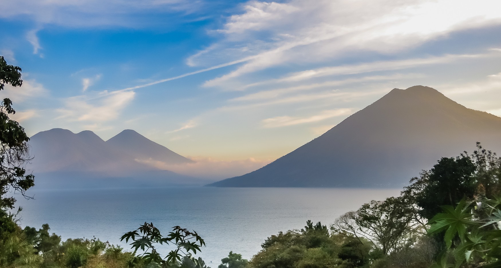 Lake Atitlan in Guatemala with volcanoes and calm water at sunrise