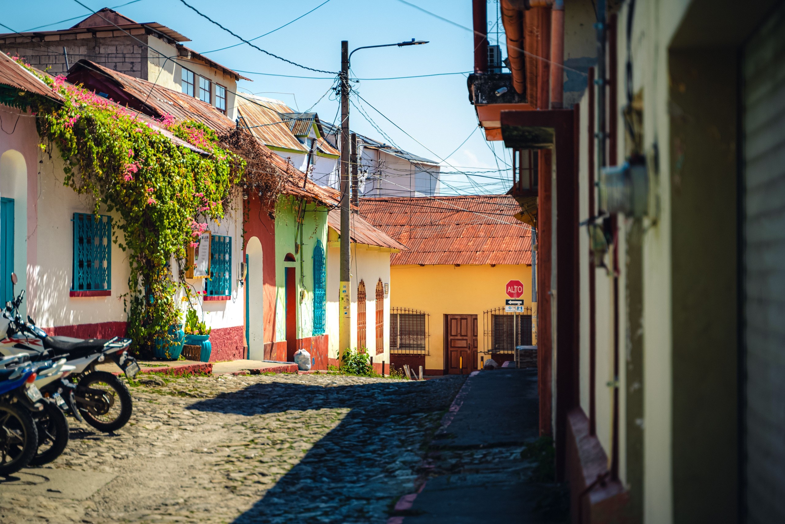 Cozy cobblestone street with a line of parked motorcycles in Flores, Guatemala