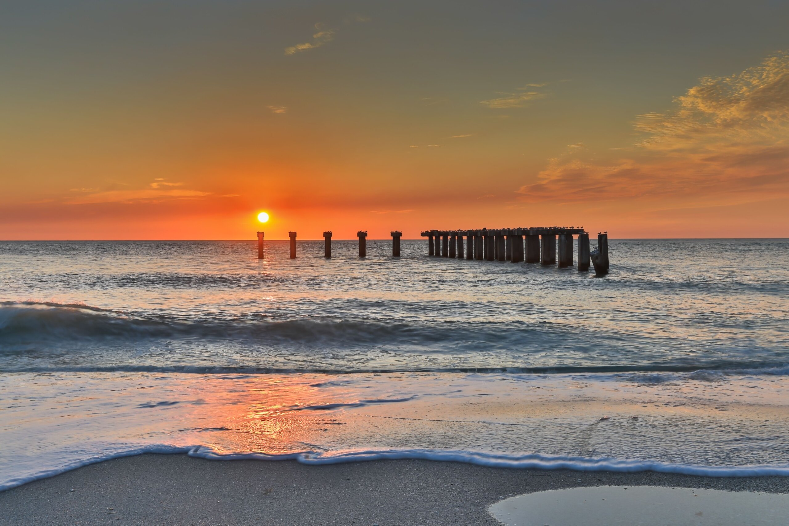 Idyllic sunset in Florida at Boca Grande Island, featuring a picturesque old stone pier and pilings
