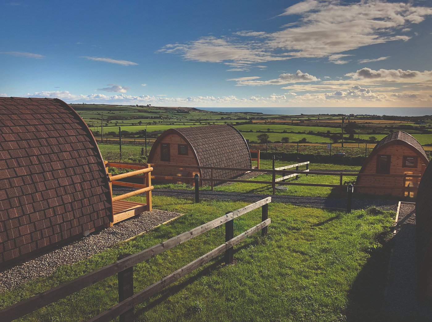 glamping pods in Irish countryside with green fields and coastal views