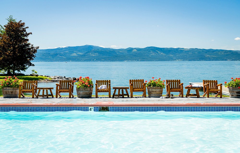 Resort pool with wooden lounge chairs overlooking Flathead Lake and the Rocky Mountains at Flathead Lake Lodge, Montana
