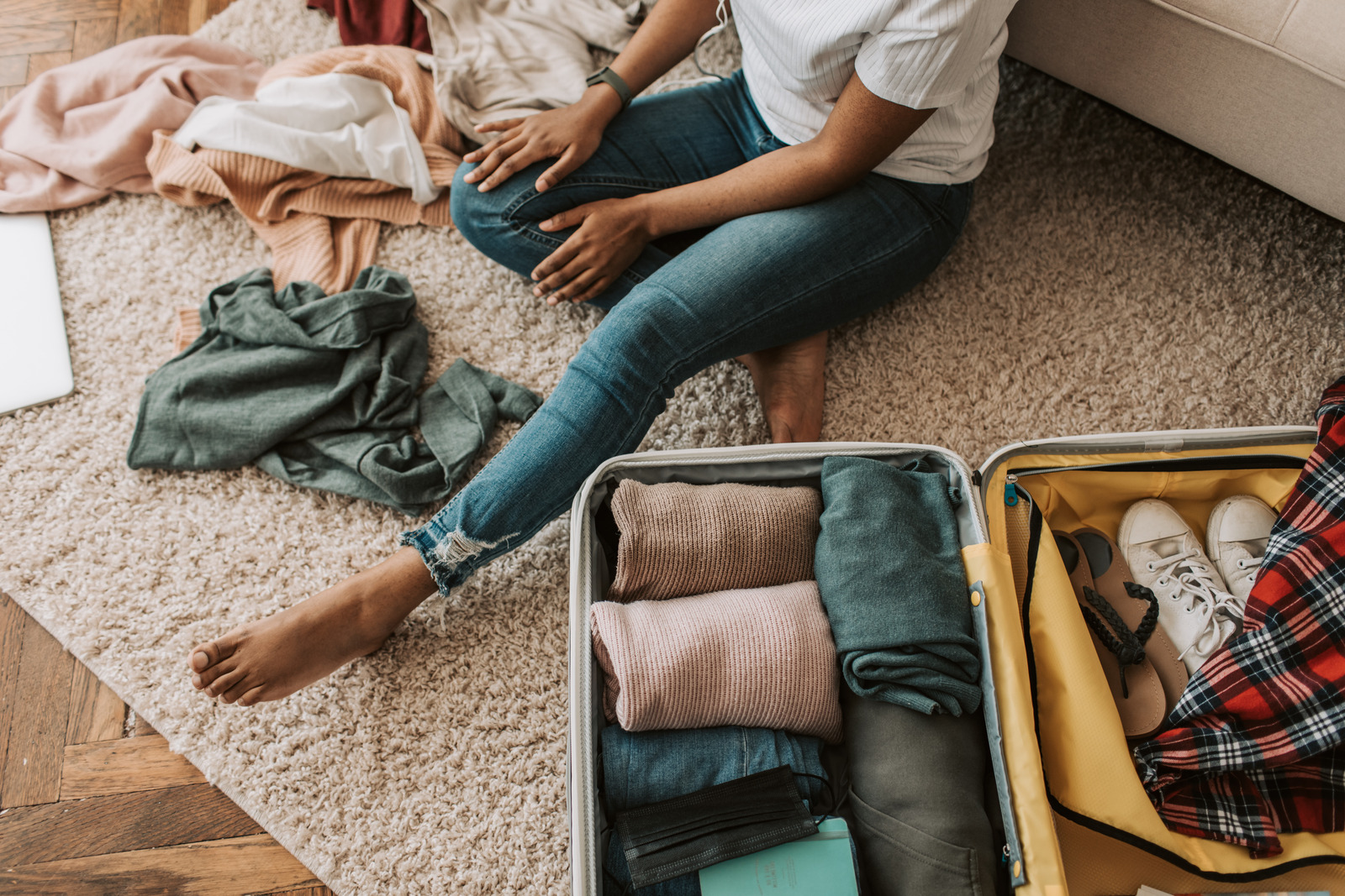 traveler packing suitcase on floor with clothes and shoes showing travel packing personality