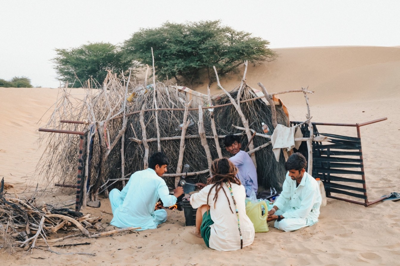 travelers sitting with locals in desert experiencing slow travel and cultural connection