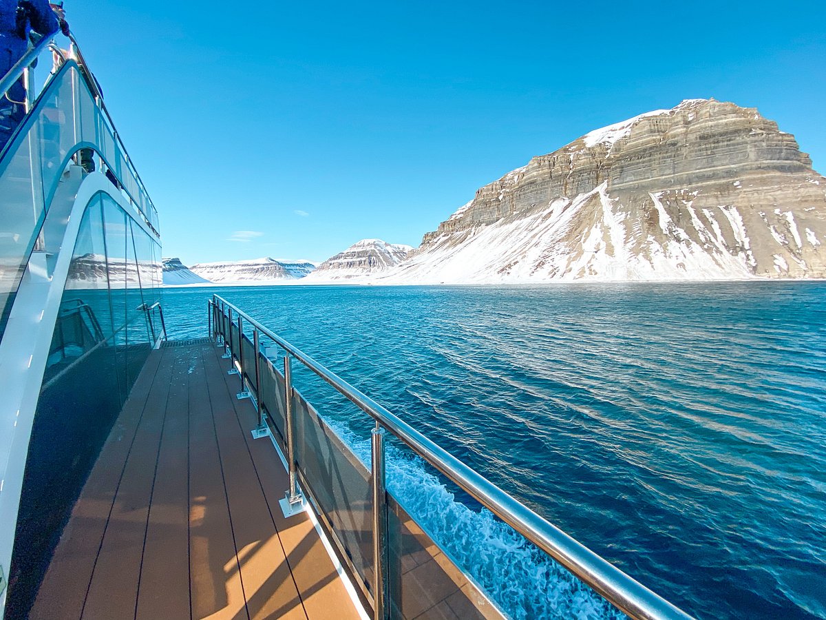 Small cruise ship sailing through icy fjord landscape