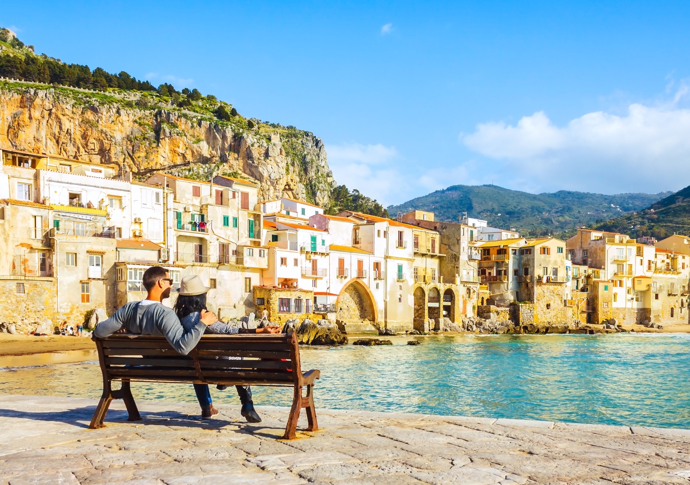 Couple relaxing beside colorful Mediterranean coastal village during vacation
