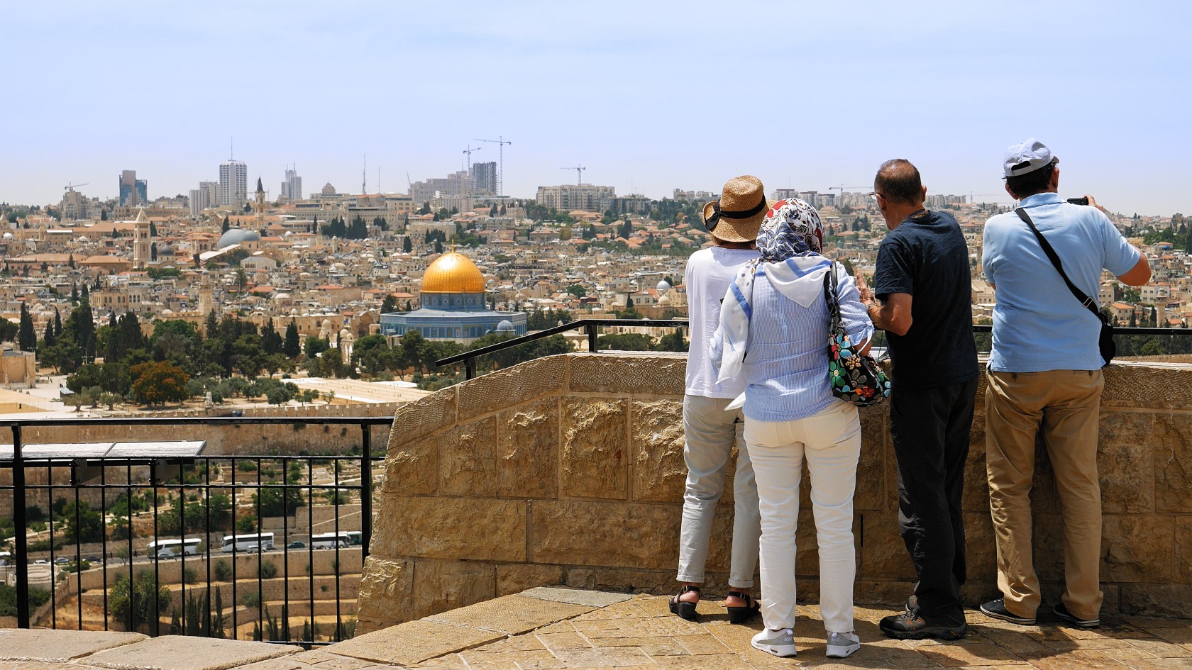 The guide shows the Jerusalem Old City view to the tourists and pilgrims. Mount of Olives is a famous Holy Land place and it has a fantastic view to the Old Jerusalem