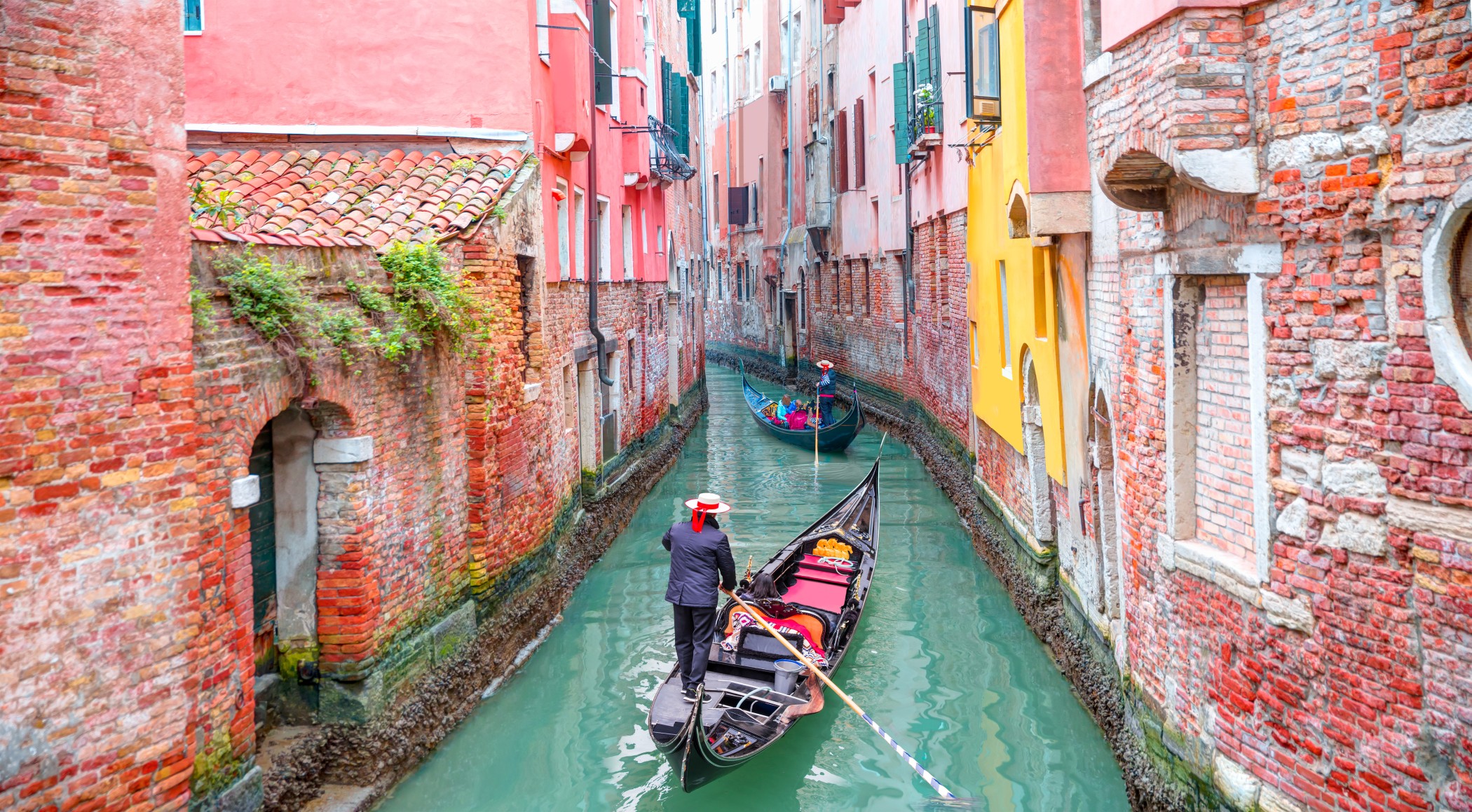 Traditional gondolas traveling through historic Venice canal in Italy