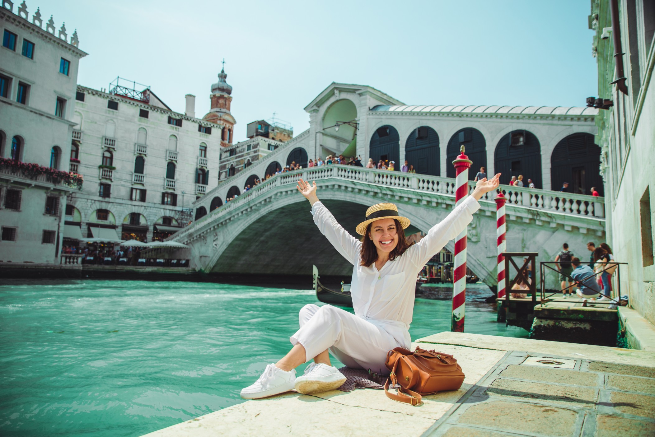 woman sitting near rialto bridge in venice italy looking at grand canal with gondolas
