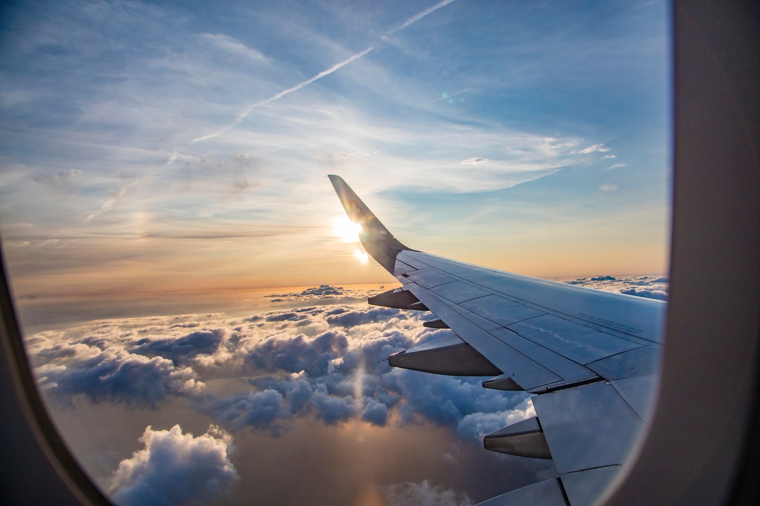 Airplane wing above clouds during sunset for an article about why flights feel longer.